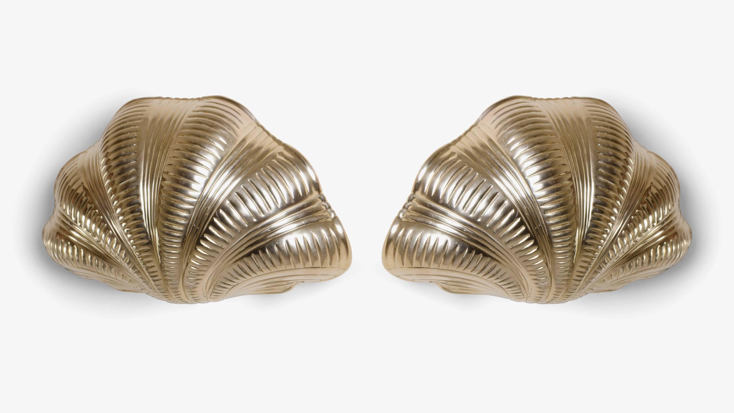 The excellence of Italian craftsmanship. A pair of artfully designed sconces from the Mid-Century, still in outstanding condition. Solid cast brass scallop motif forms are delicately engraved giving them a natural form. Mounted to a wall, the pair