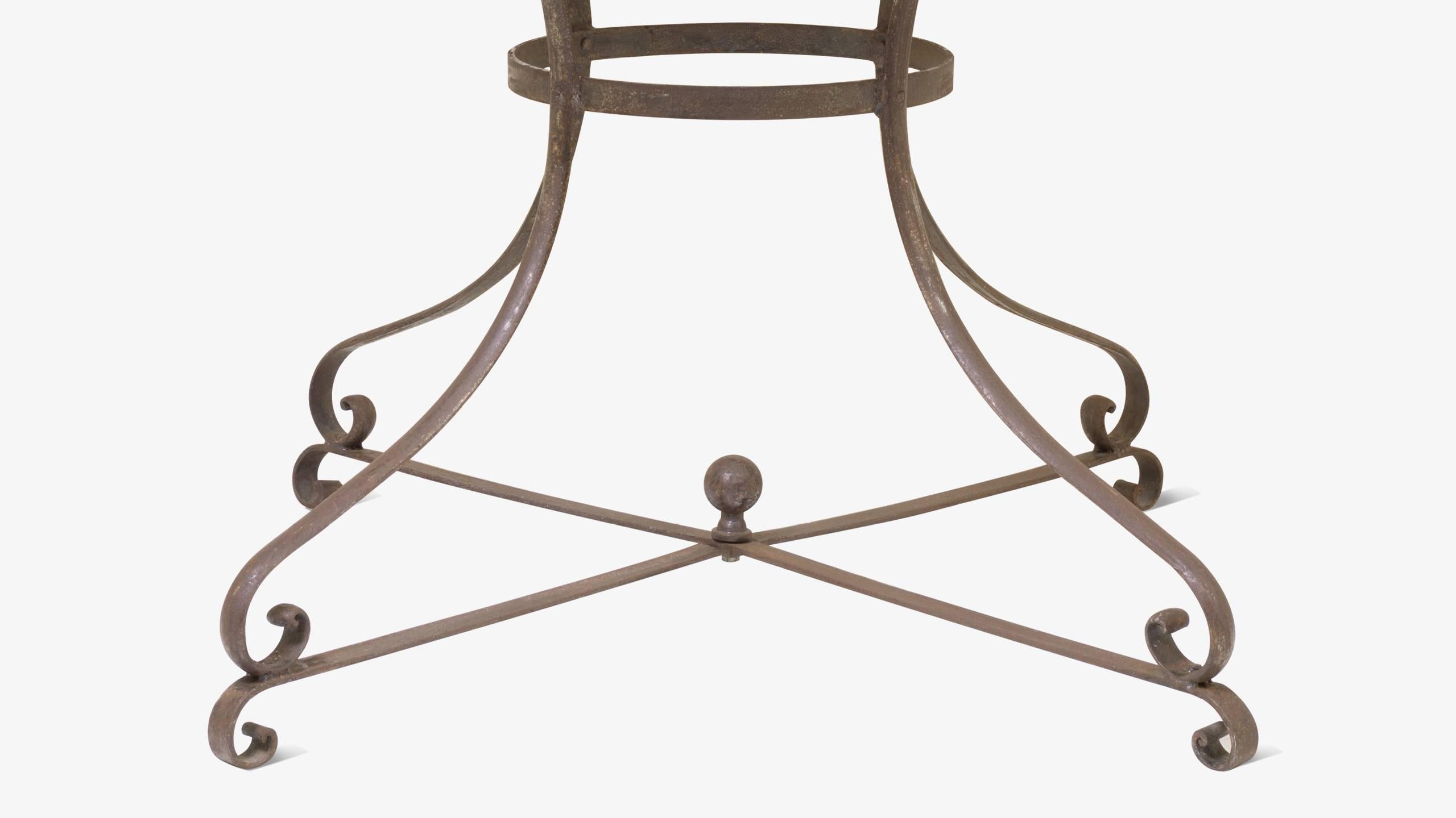A piece rich with history and patina. A generously sized Guéridon design bistro table crafted completely out of iron. The base is a simple yet elegant wrought iron classic design with delicate curves and an impressive ball finial at its center. The