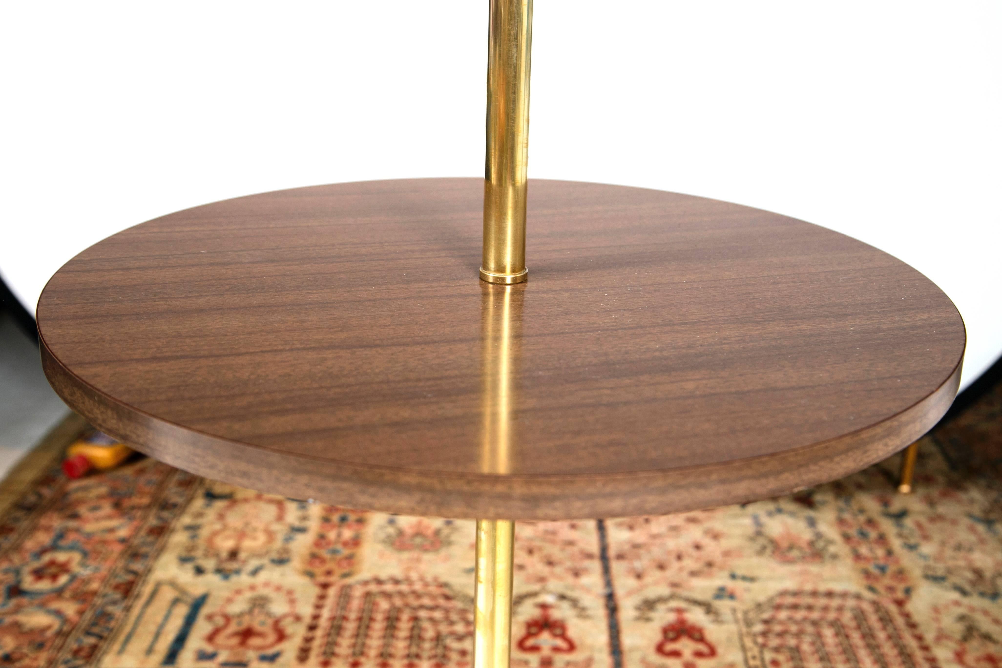 The epitome of the Mid-Century. This well proportioned brass core lamp stands upon a tri-leg base that rises up to a circular formica accent table. Perfect to nestle between two club chairs or flanking a classic lounge chair. Looks brand new, great