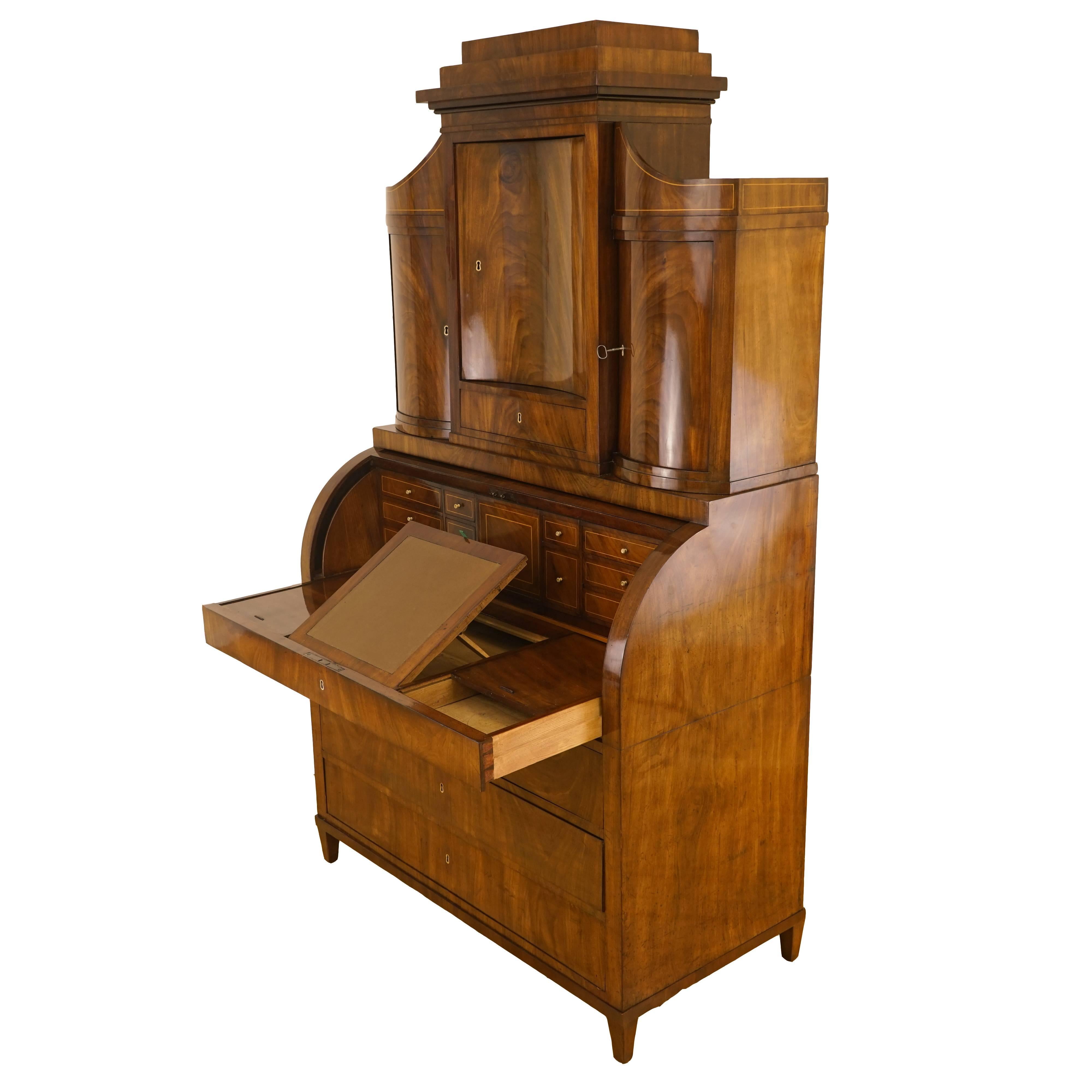 A perfect example of the wealthy, elegant Biedermeier period, this impressive, secretary is veneered in flame mahogany and birch intarsia, with bone escutcheons, secret compartments, locking drawers, tilting leather writing surface, cylinder top and