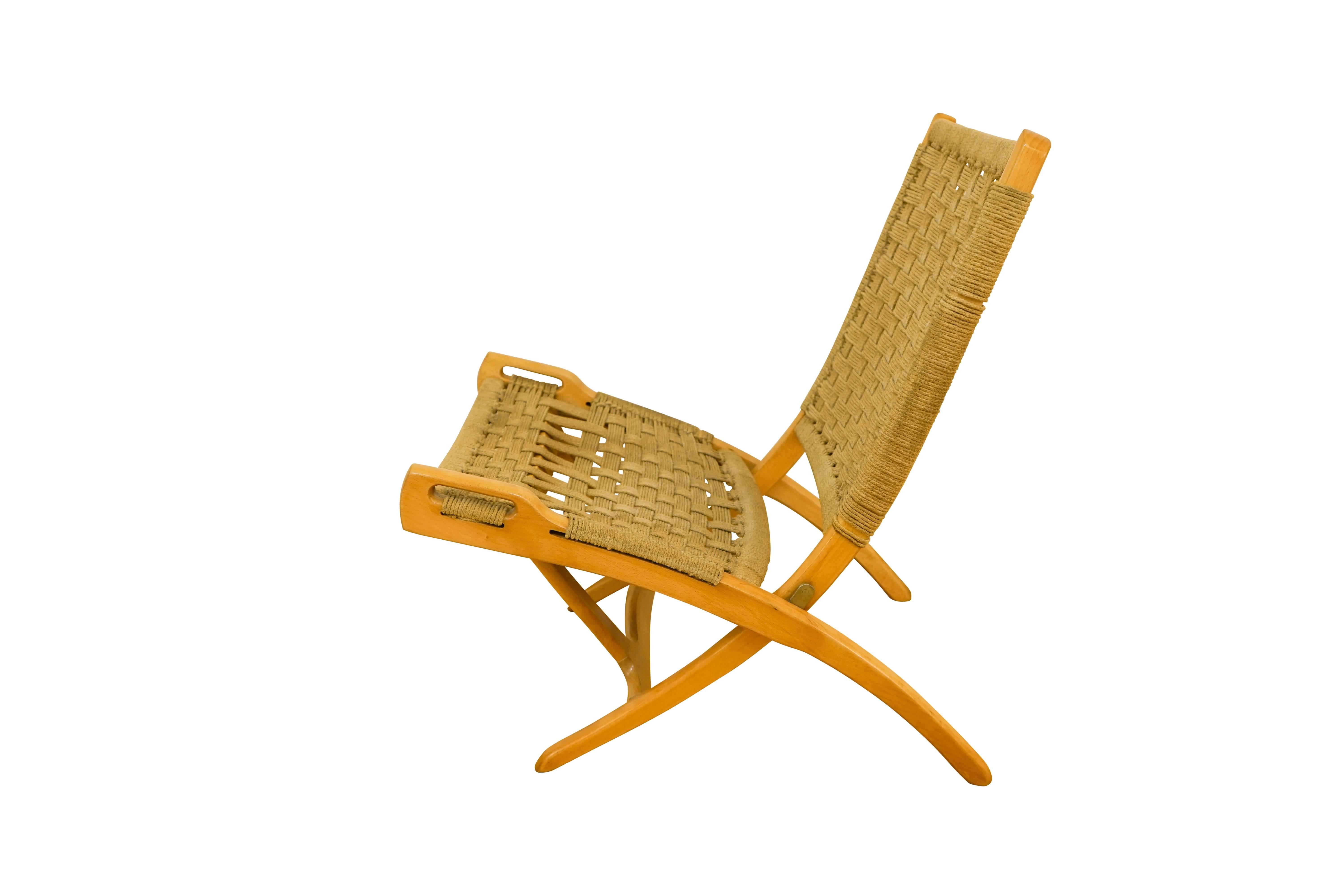 A super comfortable folding chair, perfect for a solarium or the beach, the design of which is in the style of Hans Wegner. Crafted of hewn oak and upholstered in the original sisal webbing, the chair folds for easy transport, and is designed to