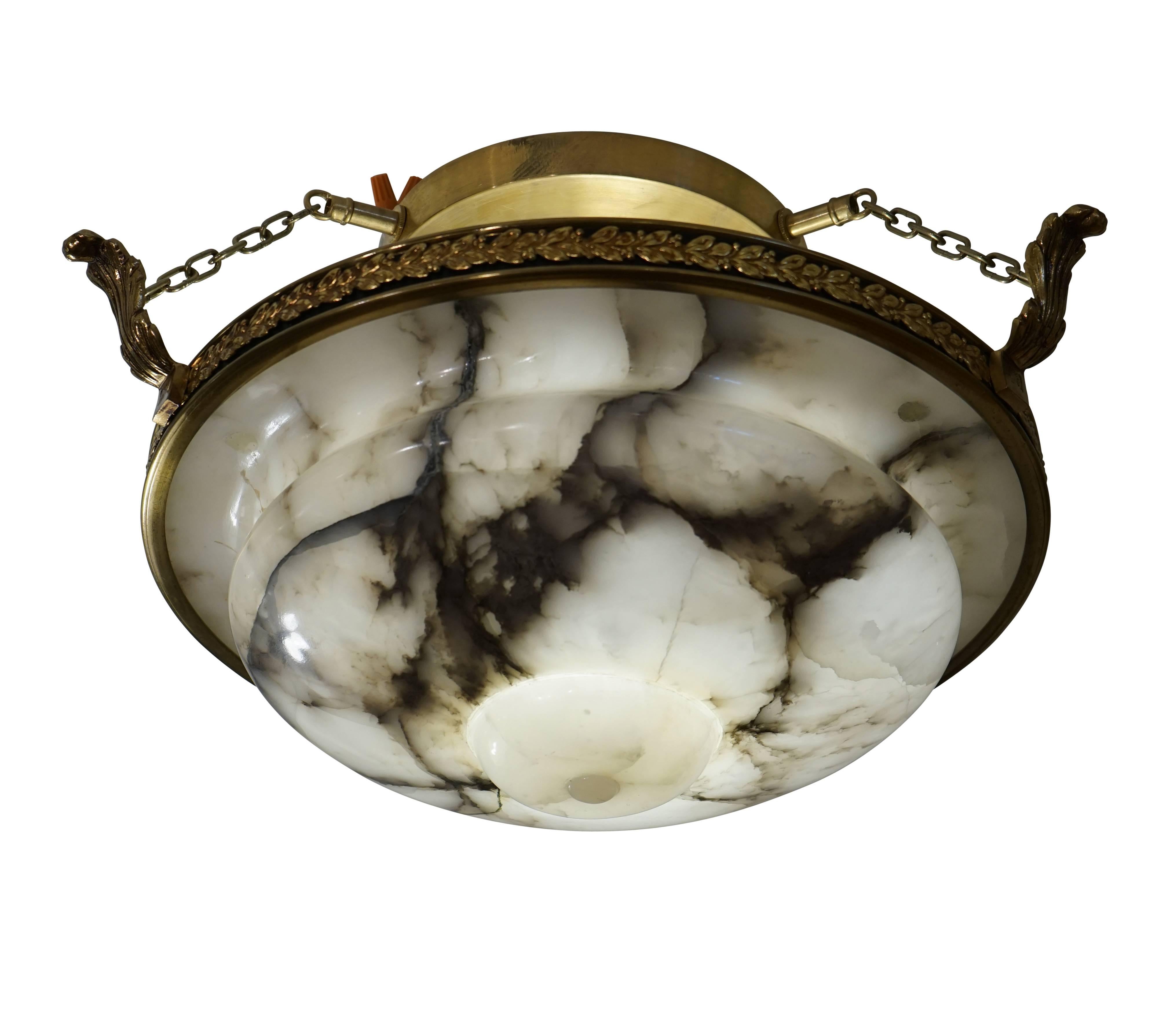 An impressive fixture which nearly hugs the ceiling, the curved and carved charcoal veined alabaster rests inside a leaf strewn brass ring. Recently rewired, the light holds one 100watt LED equivalent bulb.