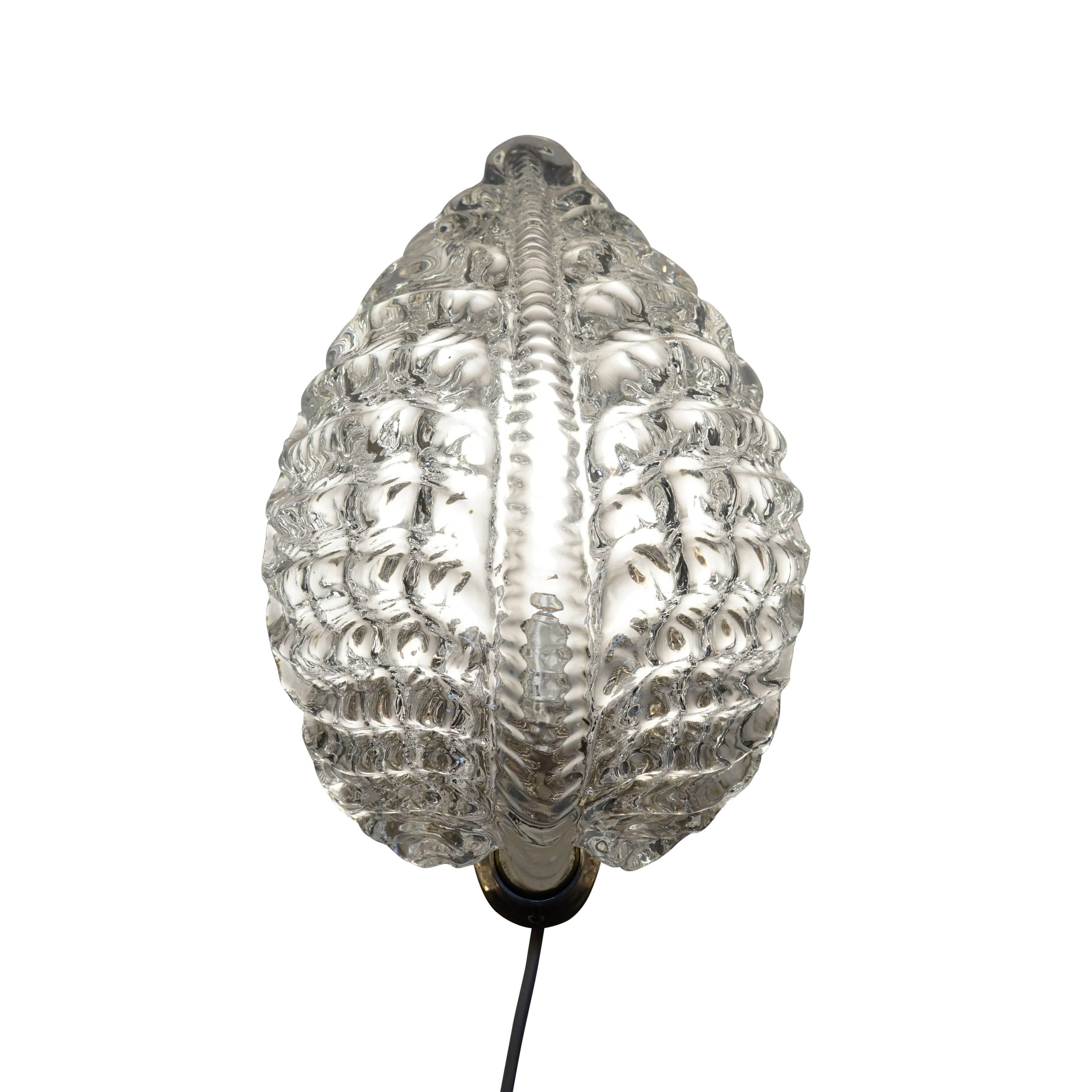 A glittering leaf shaped wall sconce from the Swedish glass legend Orrefors. Perfect for a stairway or other applications where a side or downward view is expected. The leaf shaped glass shade wraps perfectly around the light bulb and through the