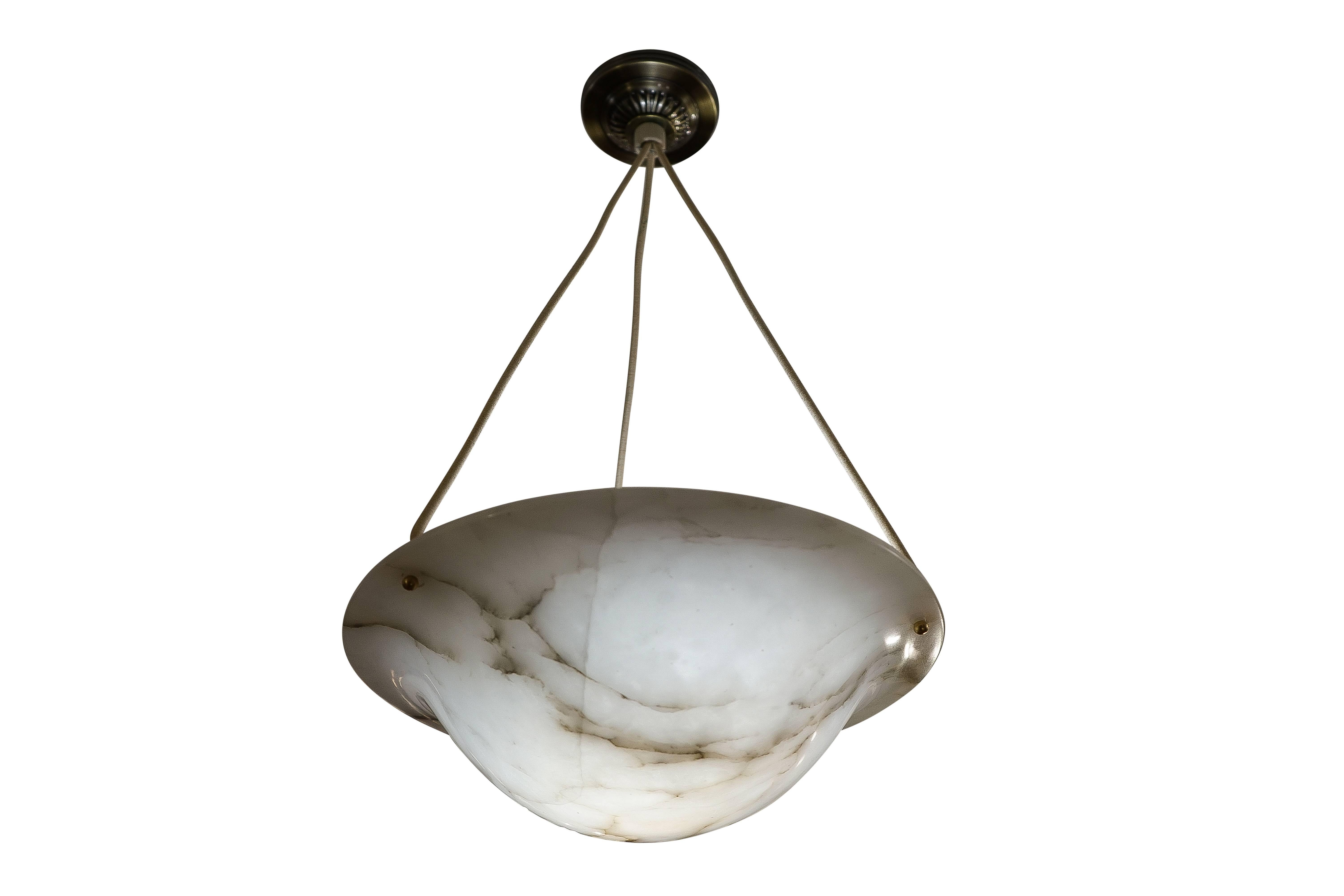 This creamy white alabaster with deep charcoal mineral veining, splays outward to cast soft light on the ceiling as well as diffusing the light through the translucent stone.  Suspended from three electrified ropes and the original brass canopy, the