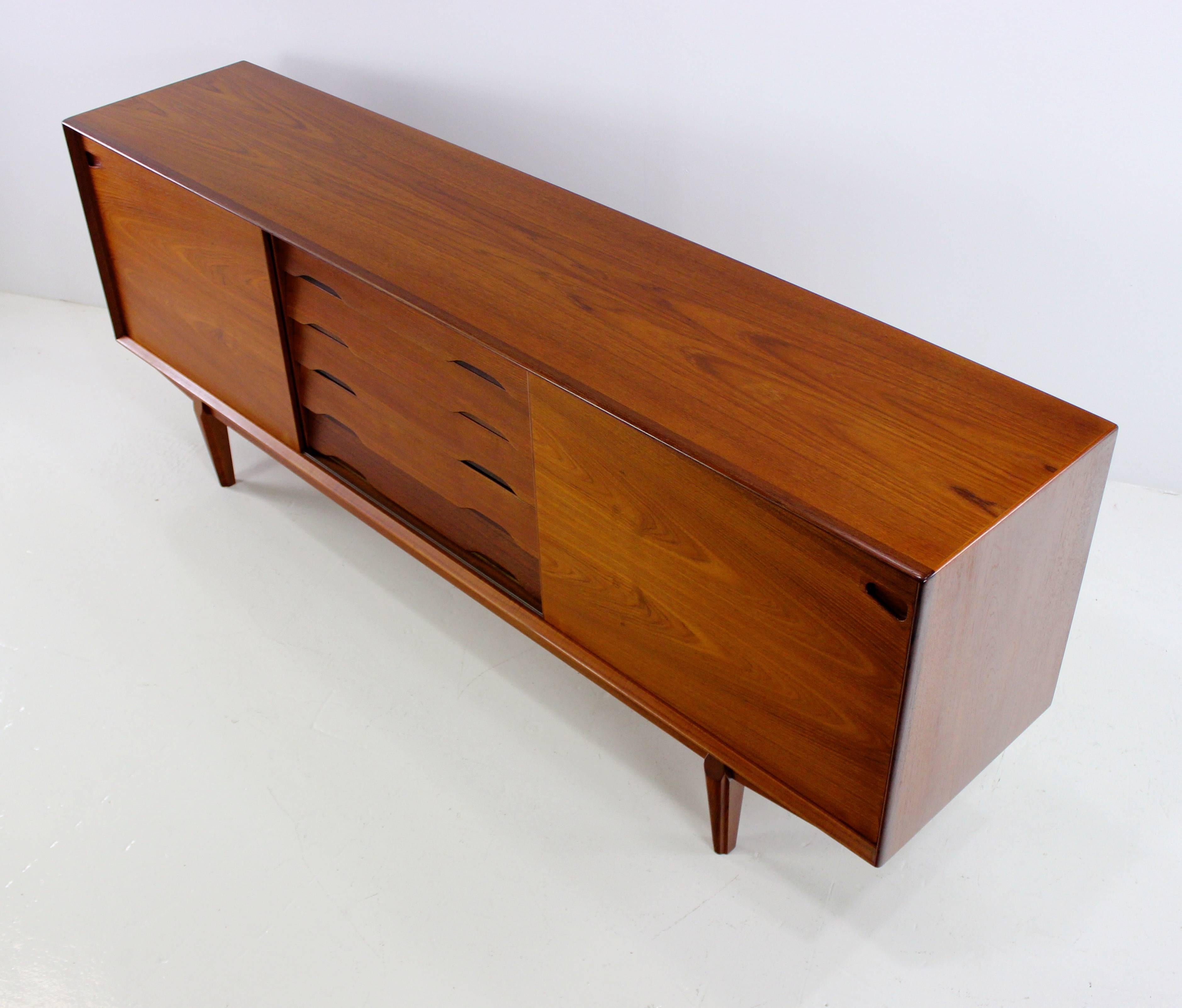 Danish modern credenza designed by Rosengren Hansen.
Rich teak with extraordinary book-matched grain.
Five drawers in the middle, the top drawer is felt lined.
Sliding doors open to adjustable shelving on each end.
Beautifully integrated door