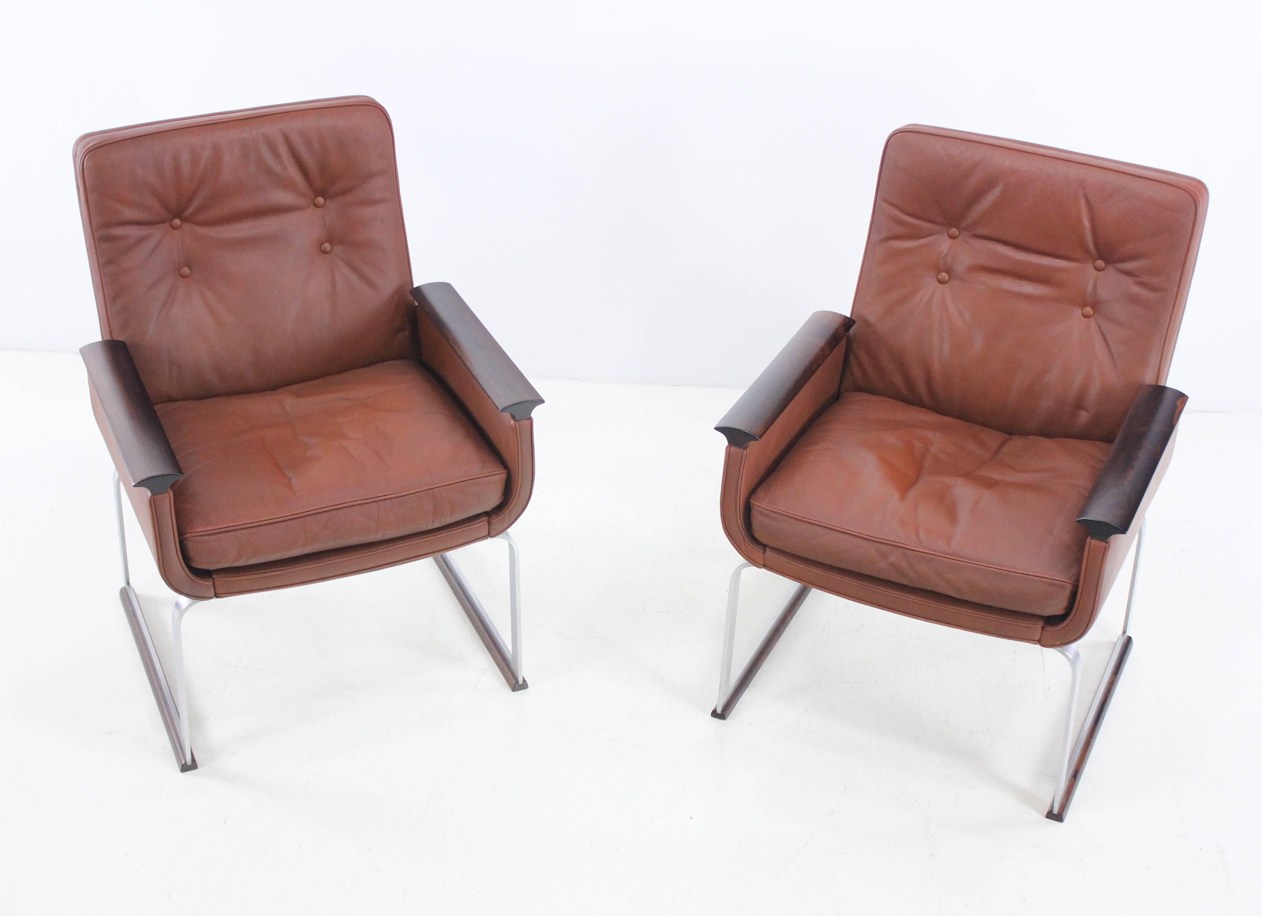 Two Scandinavian Modern armchairs.
Designed to fit in a variety of applications from commercial to residential.
Made Norway by Vatne Mobler.
Brushed steel bases, rosewood arms, original leather upholstery.
Professionally restored and refinished