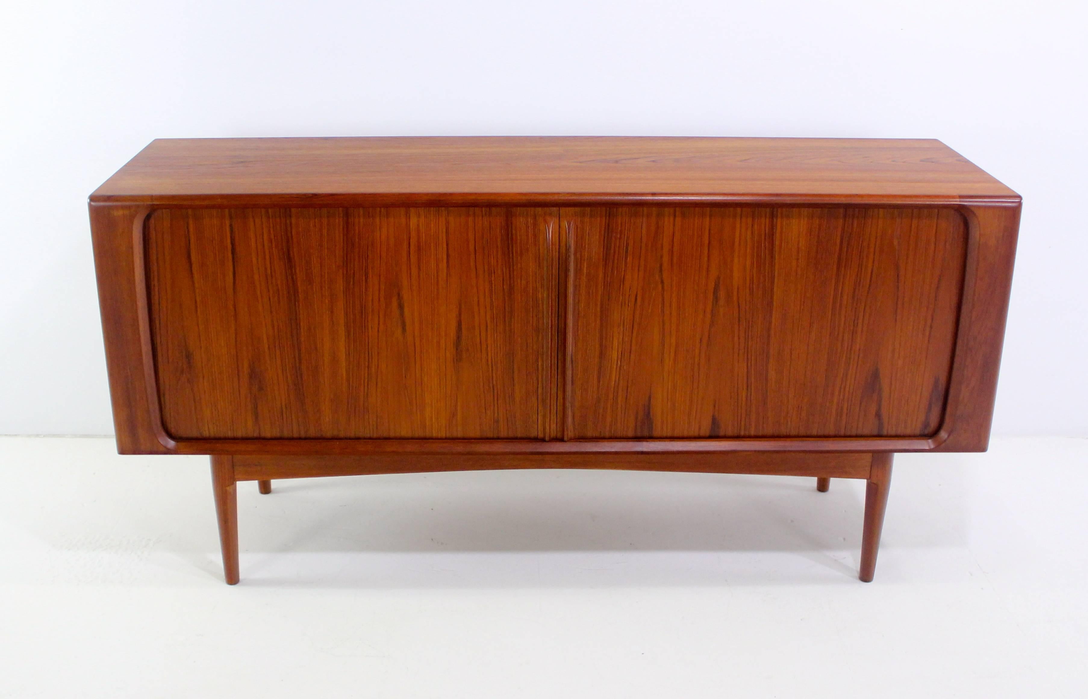 Danish modern credenza designed by Bernhard Pedersen & Son.
Richly grained teak.
Tambour doors with sculptural handles glide open to three removable drawers in the middle, adjustable shelves on each end.
Dramatic dimensional Silhouette from every