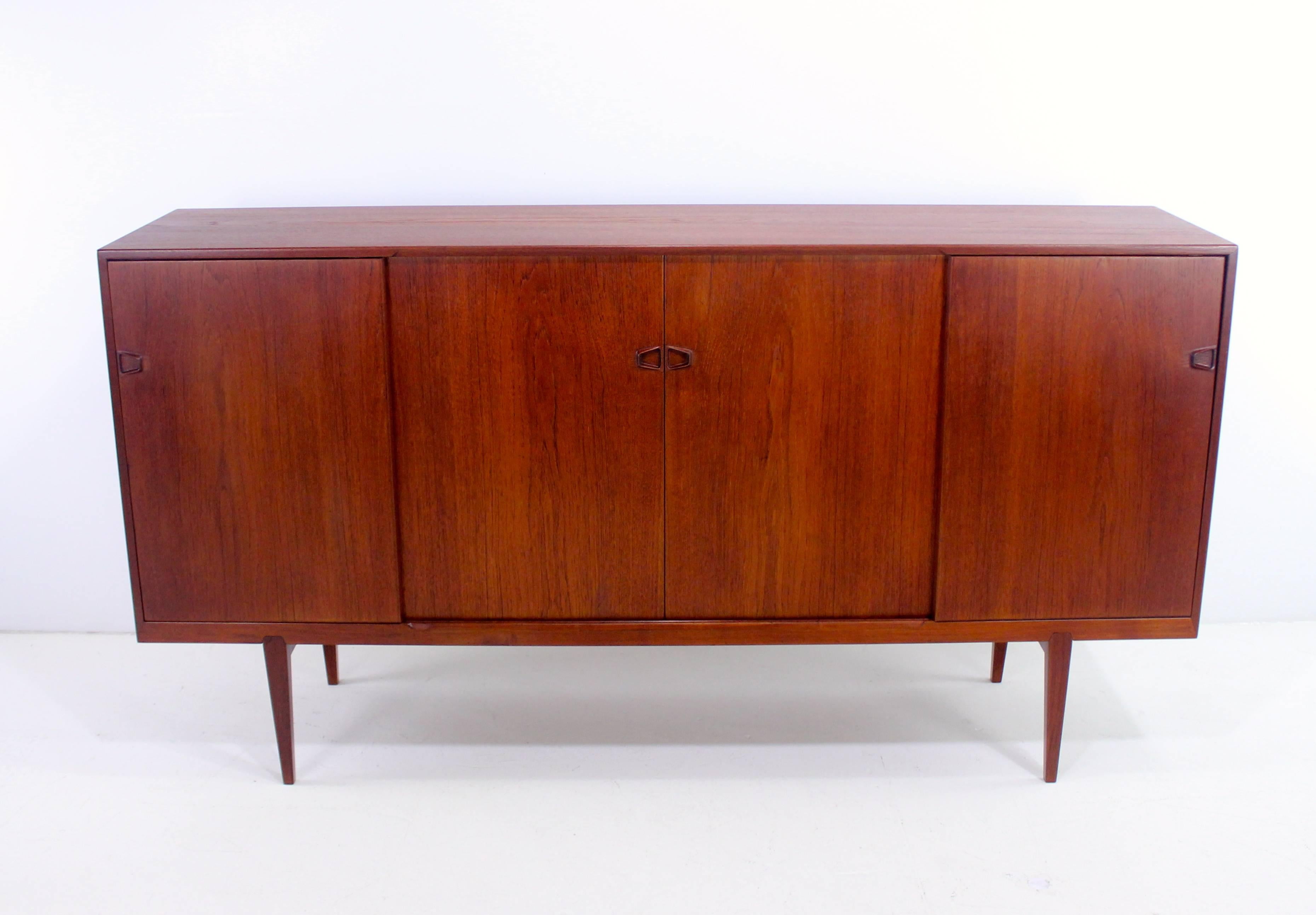 Danish modern credenza designed by Rosengren Hansen.
Rich teak with book matched grain.
Seven felt-lined drawers in center. Adjustable shelving in center right and on each end.
Semi-finished on the back.
Professionally restored and refinished by