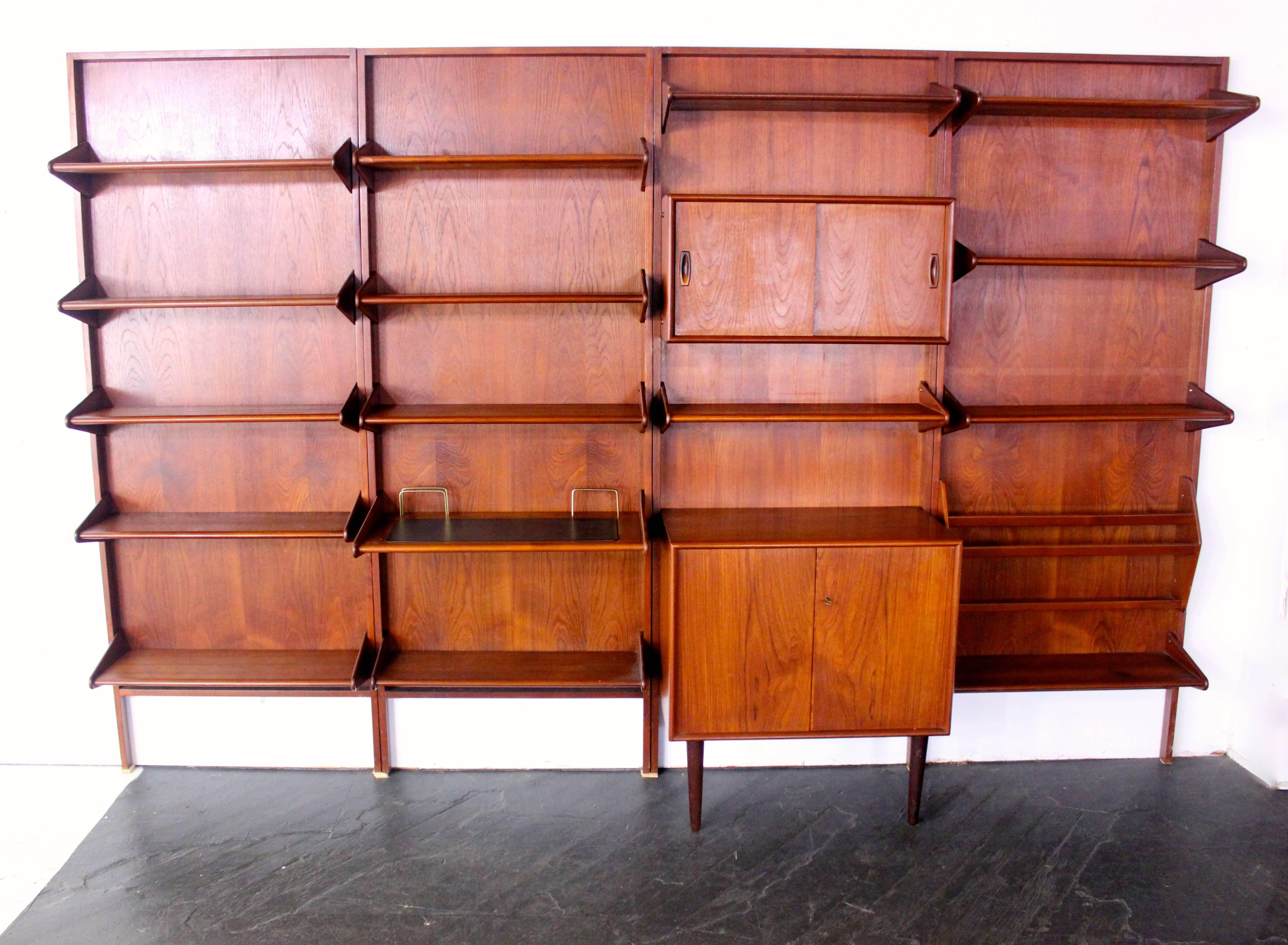 Danish modern wall-mounted unit designed by Arne Hovmand Olsen.
Impressive storage and display capacity in richly grained teak.
Features: Four bays with wall-mounted back panels, one locking cabinet and smaller cabinet with sliding doors, desktop
