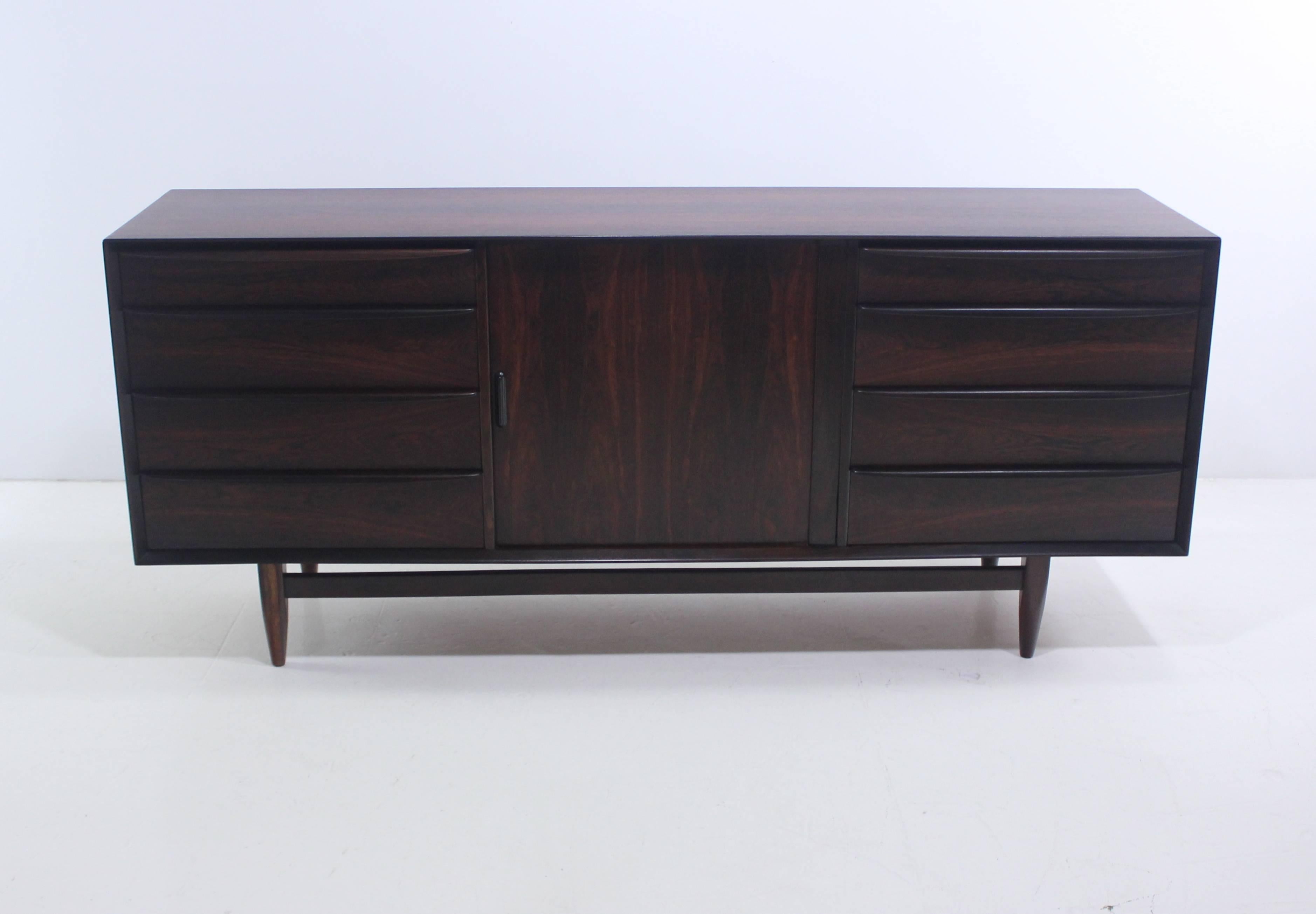 Danish modern credenza / dresser by Falster Møbelfabrik.
Deeply grained rosewood with birch interior.
Generous storage capacity, maximum functionality.
Tambour doors in middle glide open to four drawers.
Four drawers on each end.
Professionally