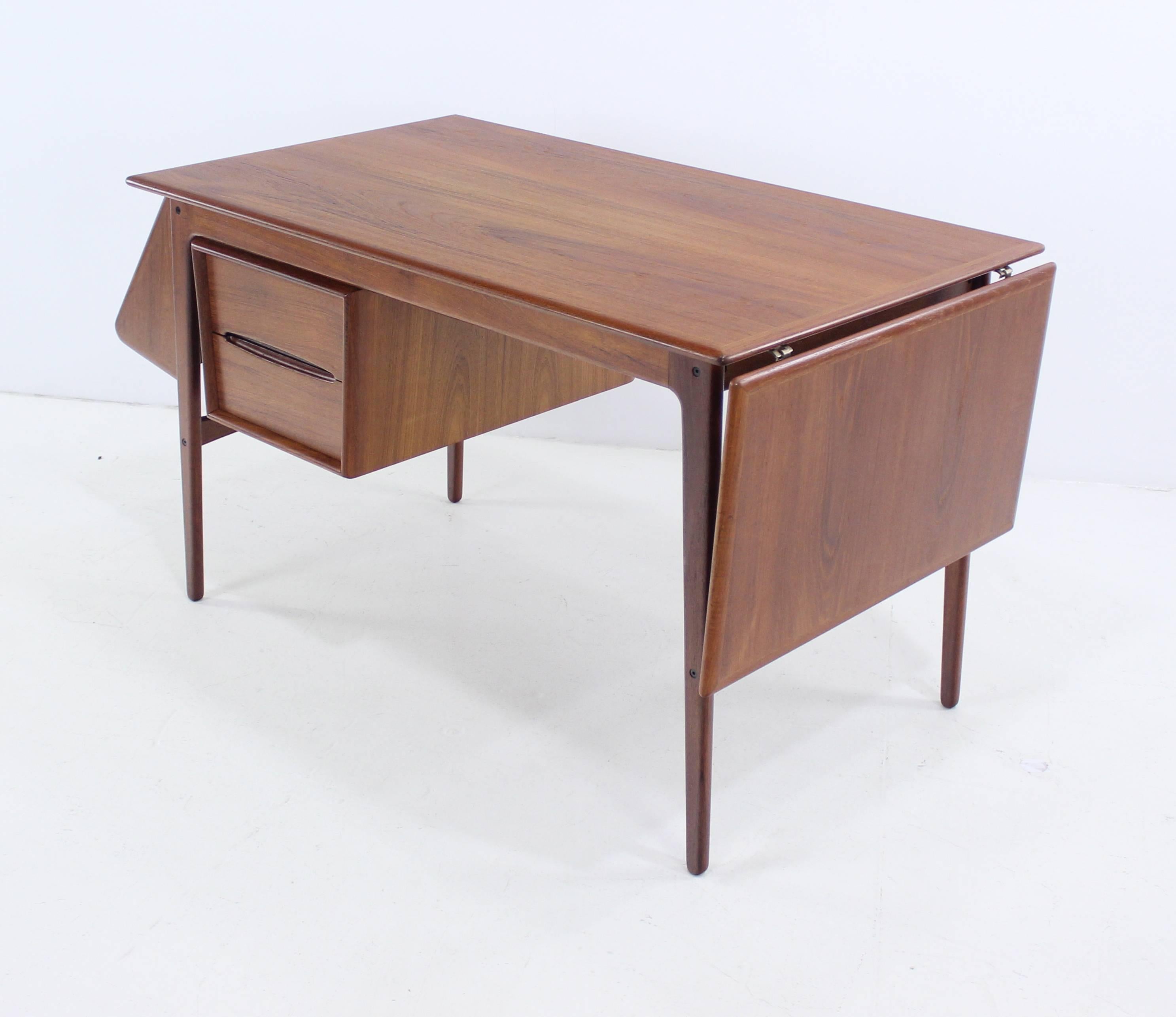 Danish modern desk by Aksel Boll Jensen.
Rich teak.
Drop-leaf provides superior versatility and overall width of 68".
Two drawer unit positionable from left to right.
Book shelf on left.
Ultimate function and adaptability.
Professionally