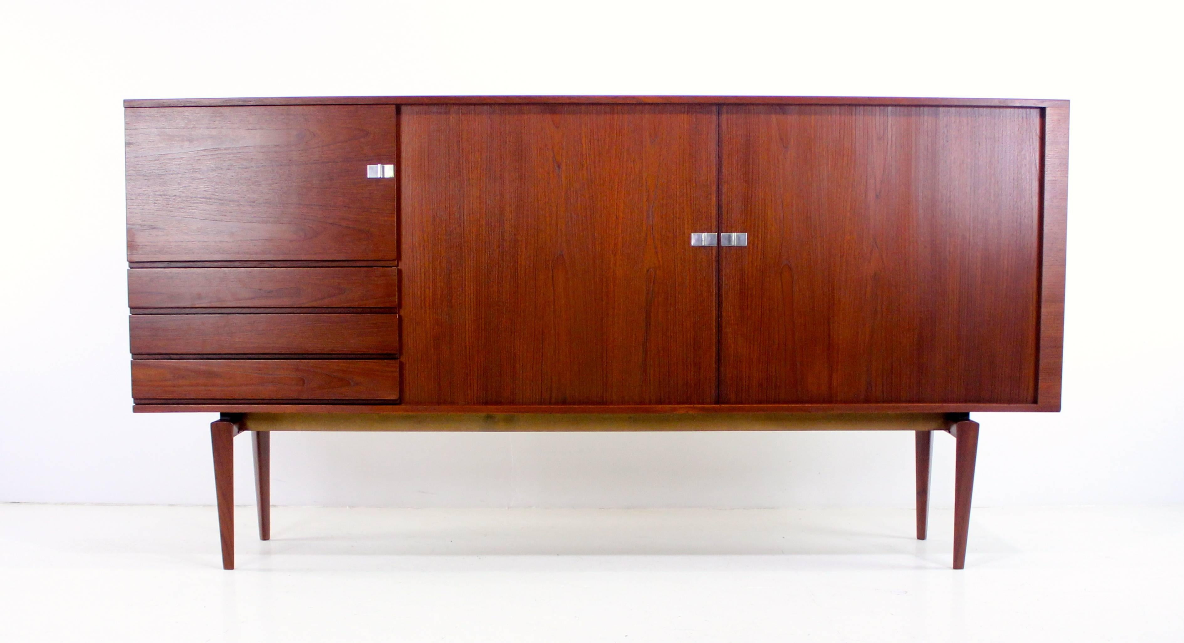 Danish modern credenza or sideboard from "Pamir" series designed by H.W. Klein in 1960.
Bramin, maker. Model #233.
Tambour doors on right, glide open to adjustable shelving.
Door on left opens to adjustable shelf above three