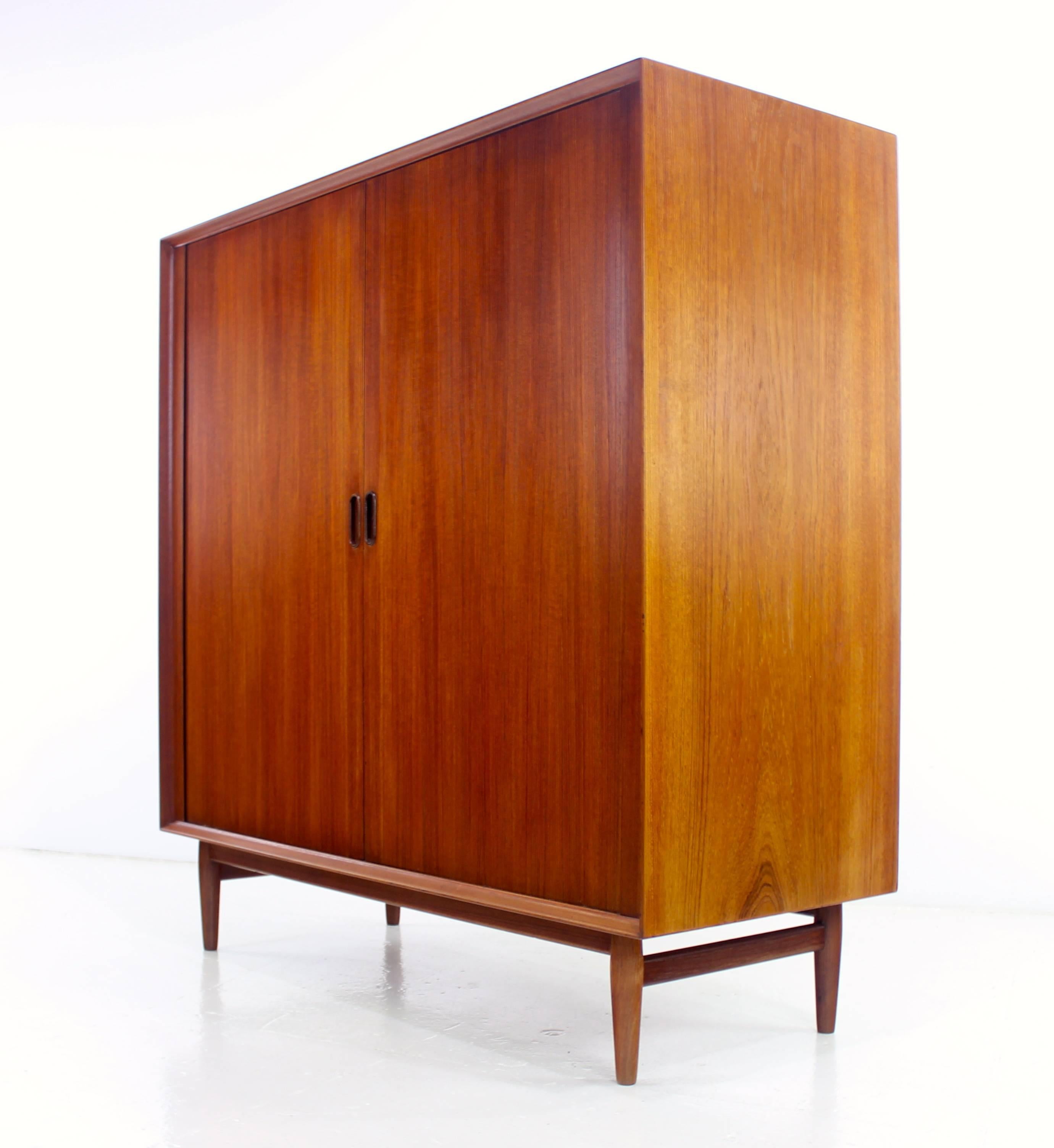 Sophisticated Danish modern gentleman's chest designed by Arne Vodder.
Richly grained teak with ultimate style and function.
Tambour doors glide open to pull-out trays on the left, two drawers and adjustable shelving on the right.
Professionally