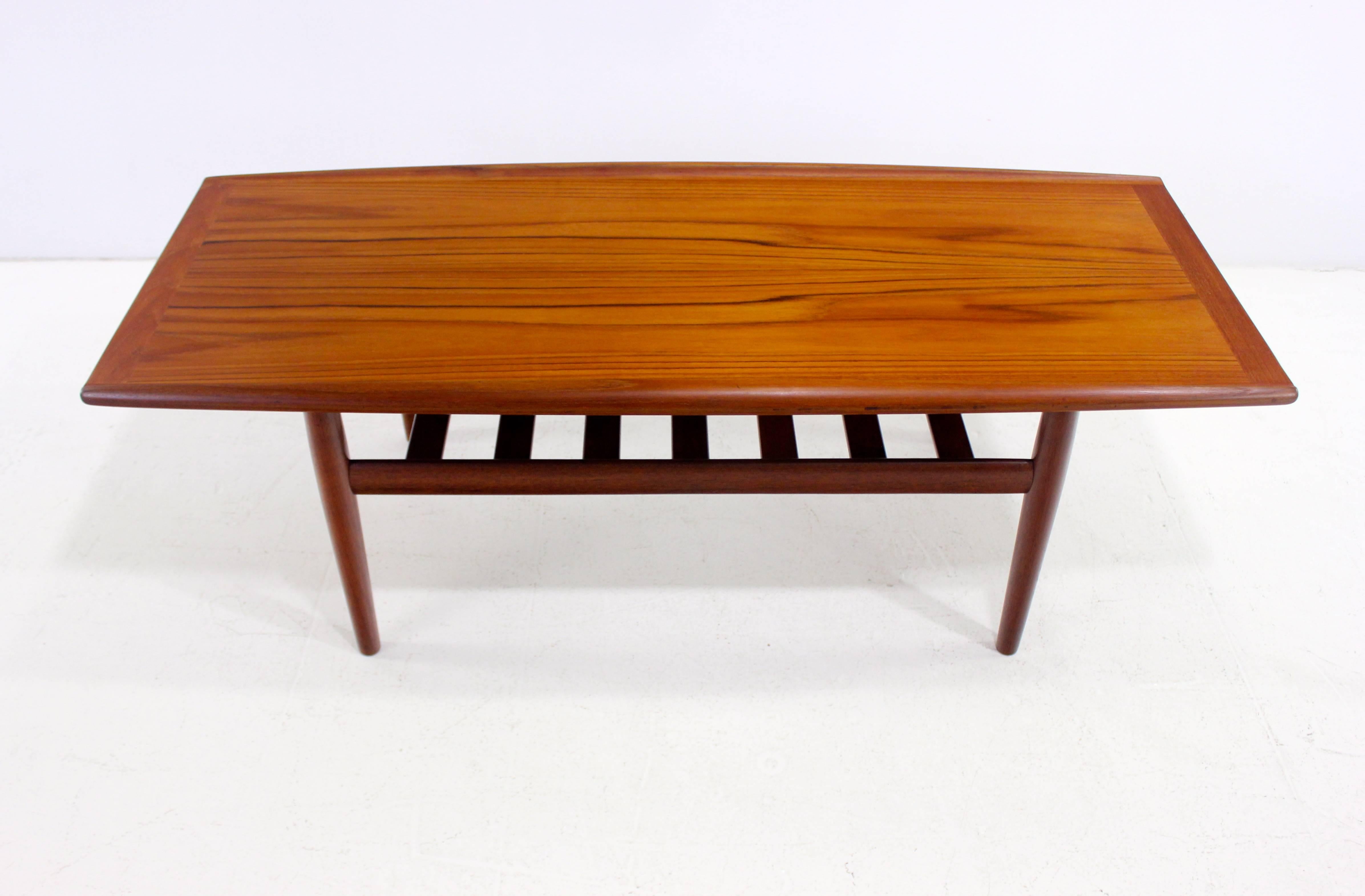 Danish modern coffee table designed by Grete Jalk.
Coveted smaller size.
Solid teak with curved edges.
Lower slated shelf.
Professionally restored and refinished by LookModern.
Matchless quality and price.
Low freight, quick ship.