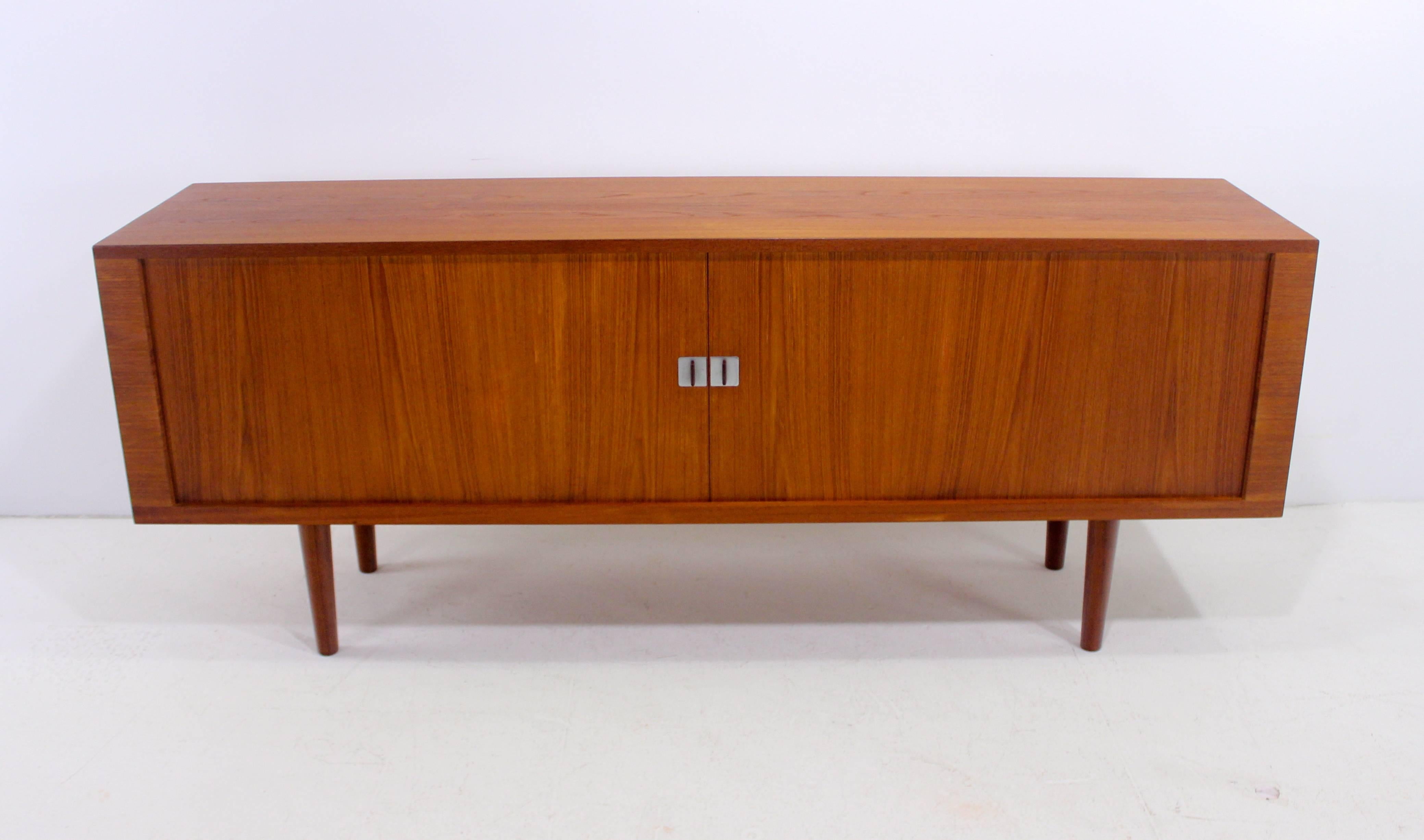 Danish modern credenza, "The President", designed by Hans Wegner.
Richly grained teak with oak interior.
Tambour doors, with elegant square metal pulls, glide open to adjustable shelves on each end. Six drawers in the middle.
Unparalleled