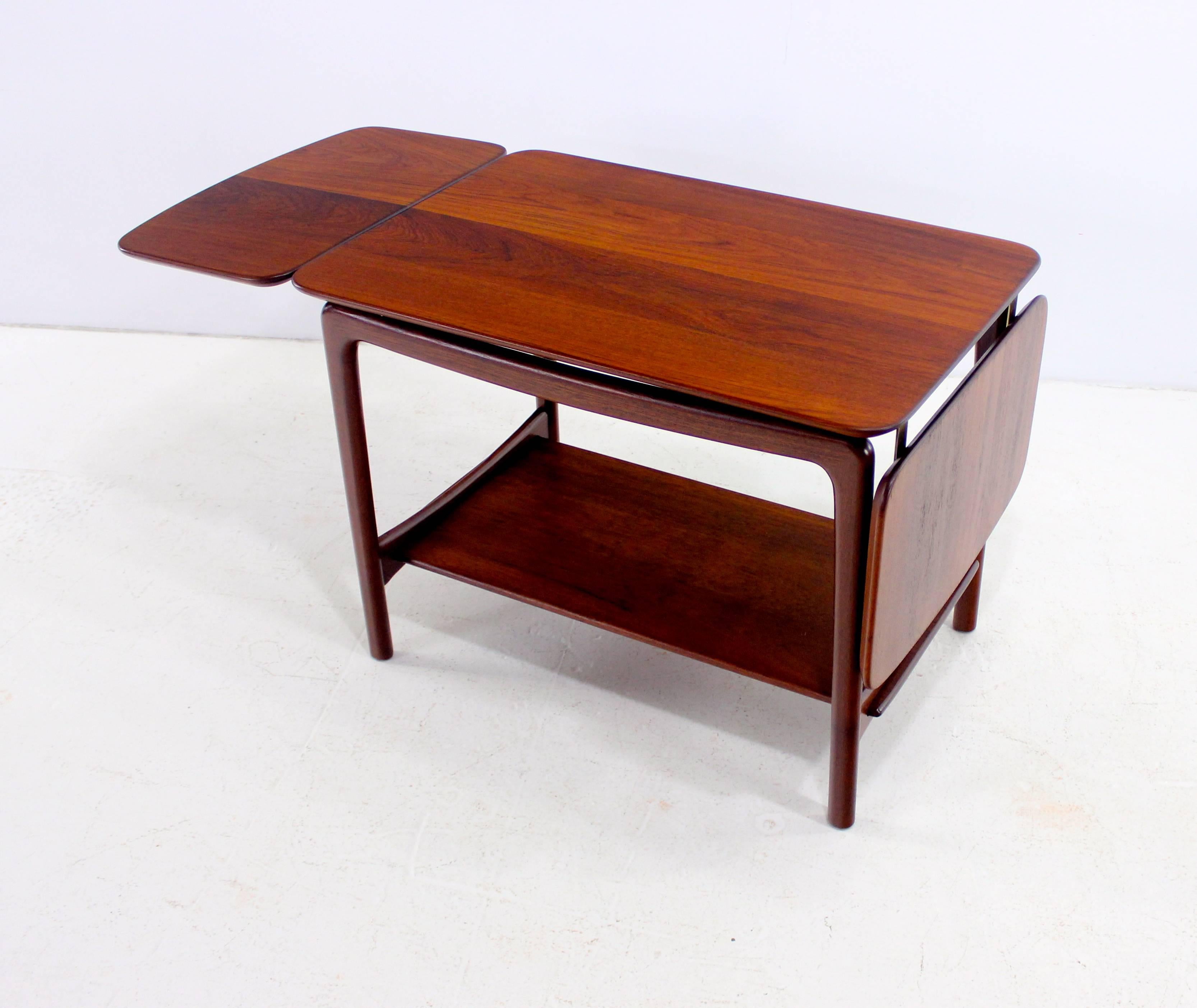 Danish modern side table designed by Peter Hvidt and Orla Mølgaard-Nielsen.
France & Son, maker.
Solid teak with brass accents.
Drop-leaves on each end provide full extension of 20.75"
Lower magazine shelf.
Matching drop-leaf coffee