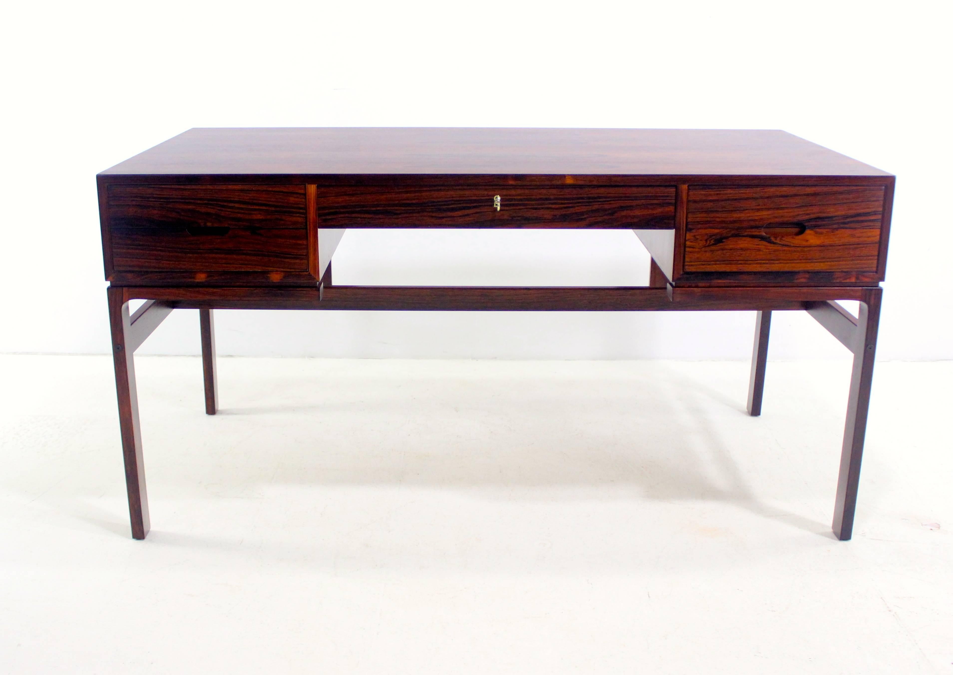 Danish modern desk designed by Arne Wahl Iversen.
Vinde Mobelfabrik, maker.
Richly grained rosewood.
Two drawers on each side. Removable pencil tray in top left drawer.
One locking drawer on middle - key included.
Front side has two cubby
