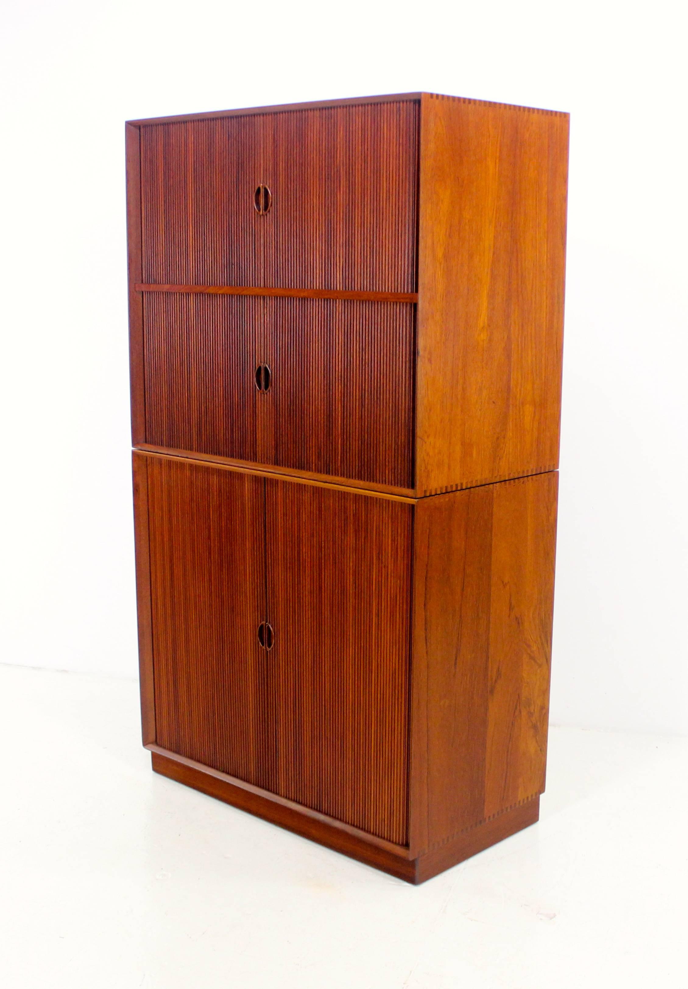 Danish modern, two part, stacking cabinet designed by Peter Hvidt.
Solid teak.
Two tambour doors on top open to storage.
One tambour door on the bottom opens to adjustable shelves.
Features signature Hvidt superior craftsmanship and