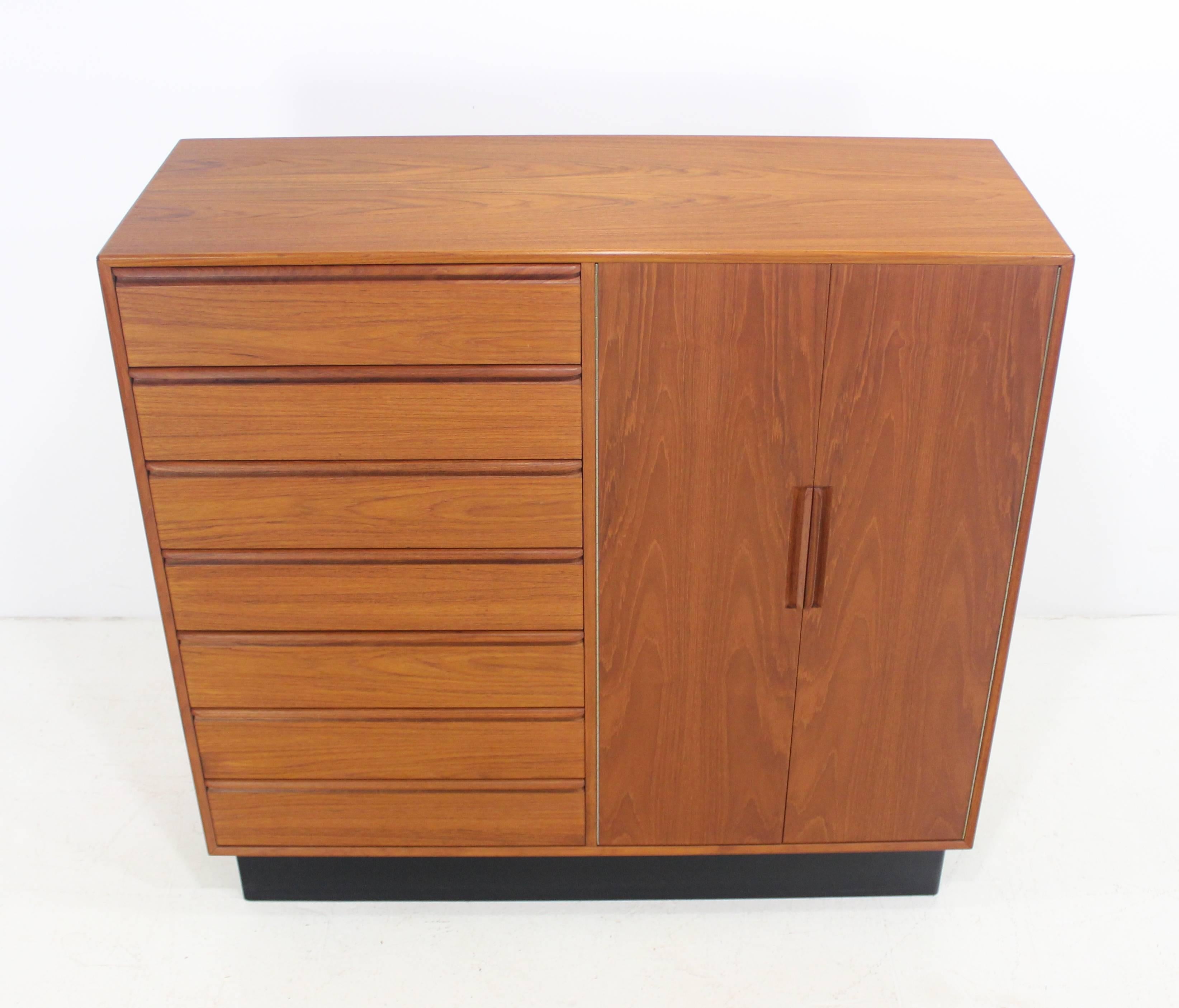 Scandinavian Modern gentleman's chest by Westnofa Furniture.
Honey colored teak with black plinth base.
Doors open to seven drawers on the right.
Seven drawers on the left.
Matchless quality and price.
Low freight, quick ship.

      