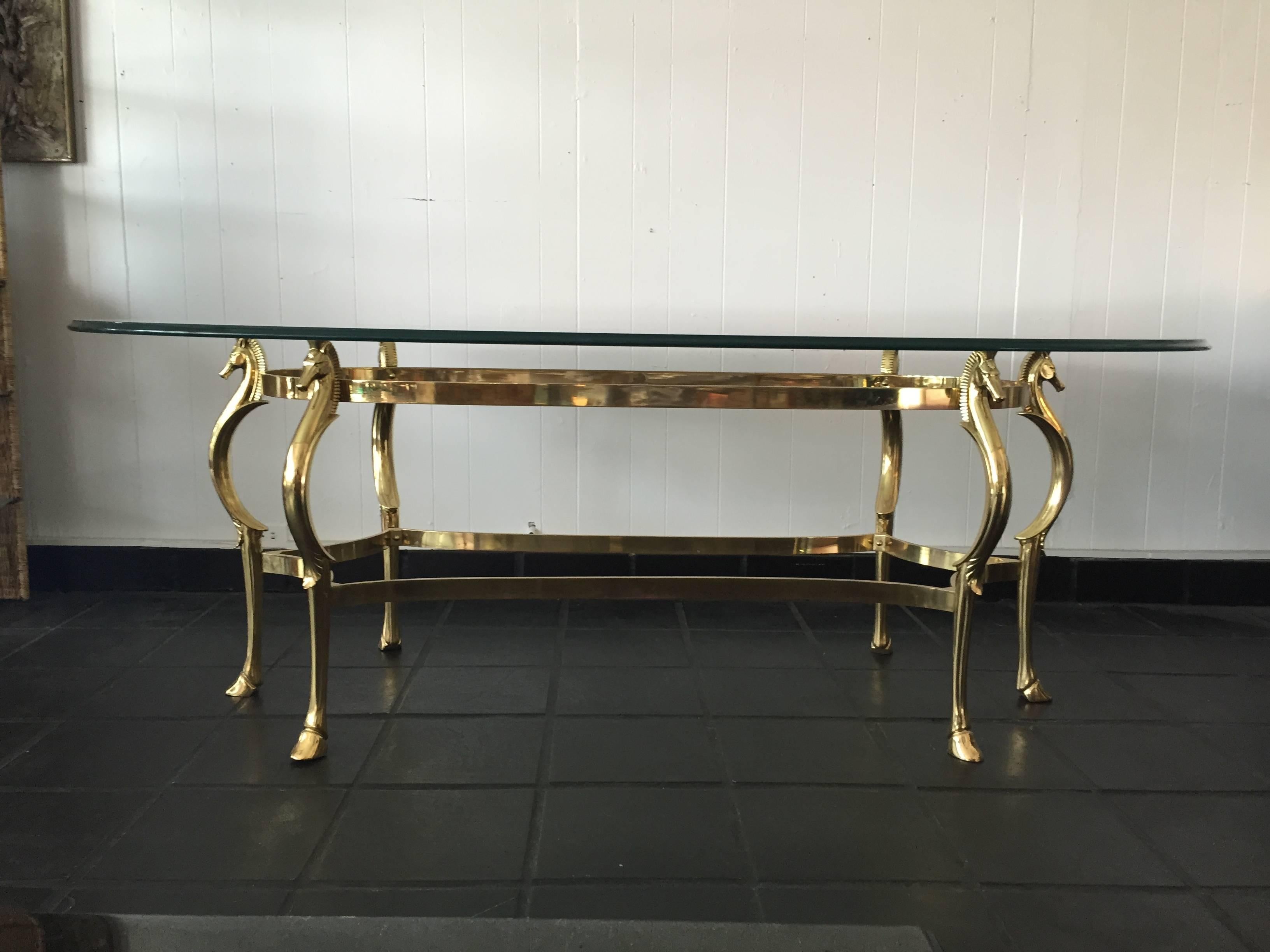 All brass oval dining table with horse head and hoof supports.