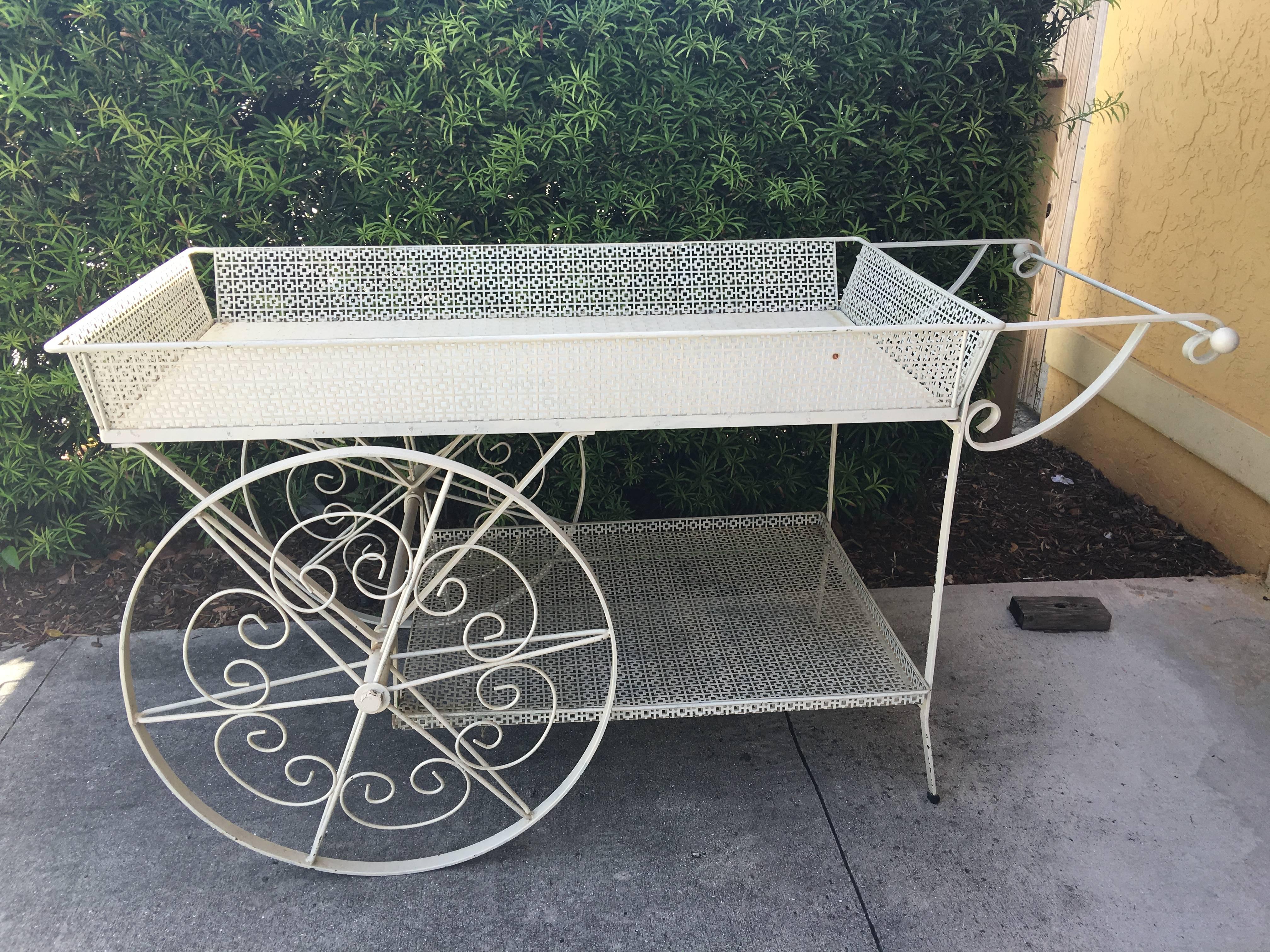 Charming vintage flower cart with detachable upper rack. In painted white this garden cart has decorative pierced metal decoration and large wheels. Height to top of rack is 64