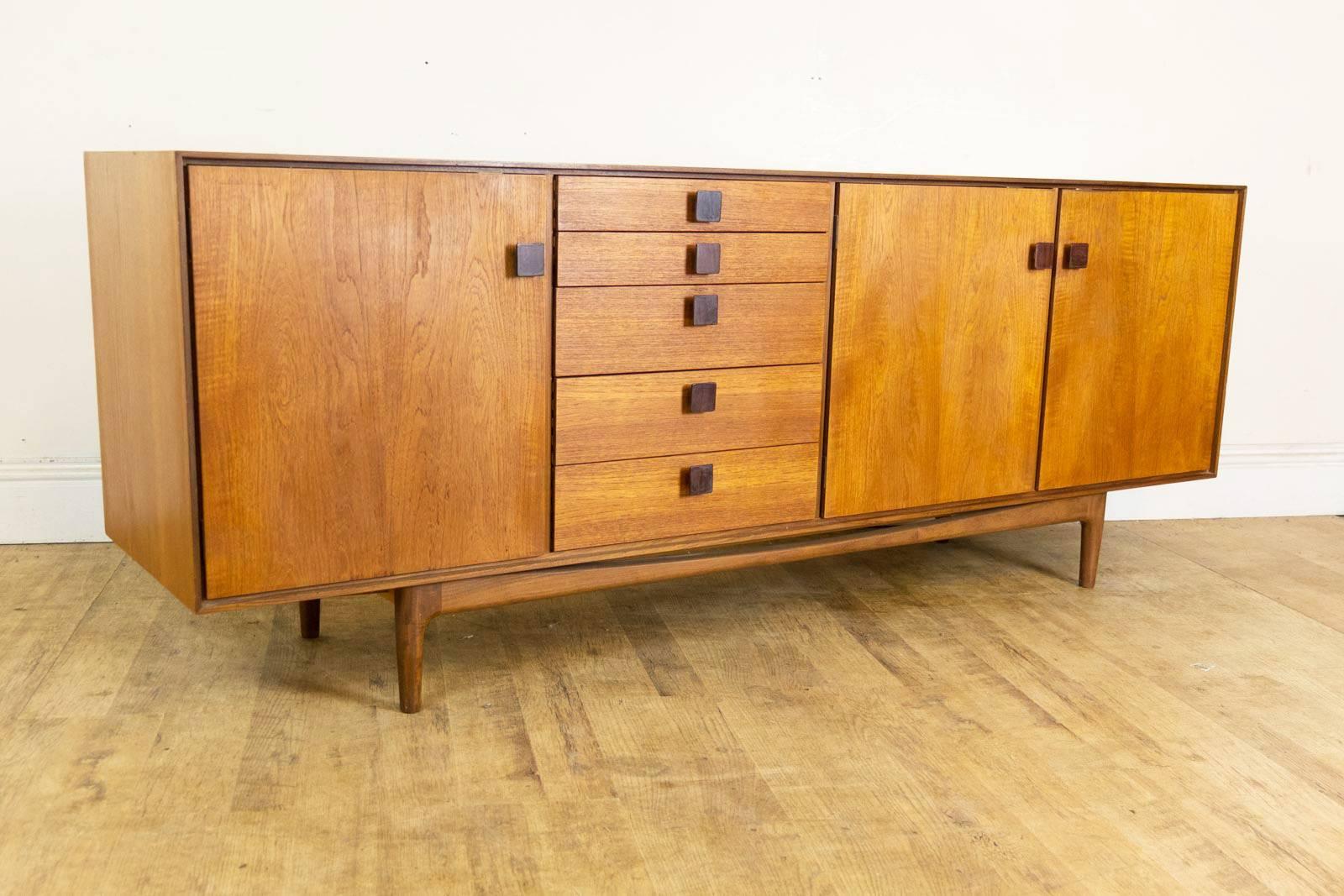 Ib Kofod Larsen Sideboard
The sideboard is made from Solid teak with rosewood handles and is very heavy and beautifully constructed.
It has a well proportioned body sitting low on a sculptured stretched base.
It has extra sliding hinges, the