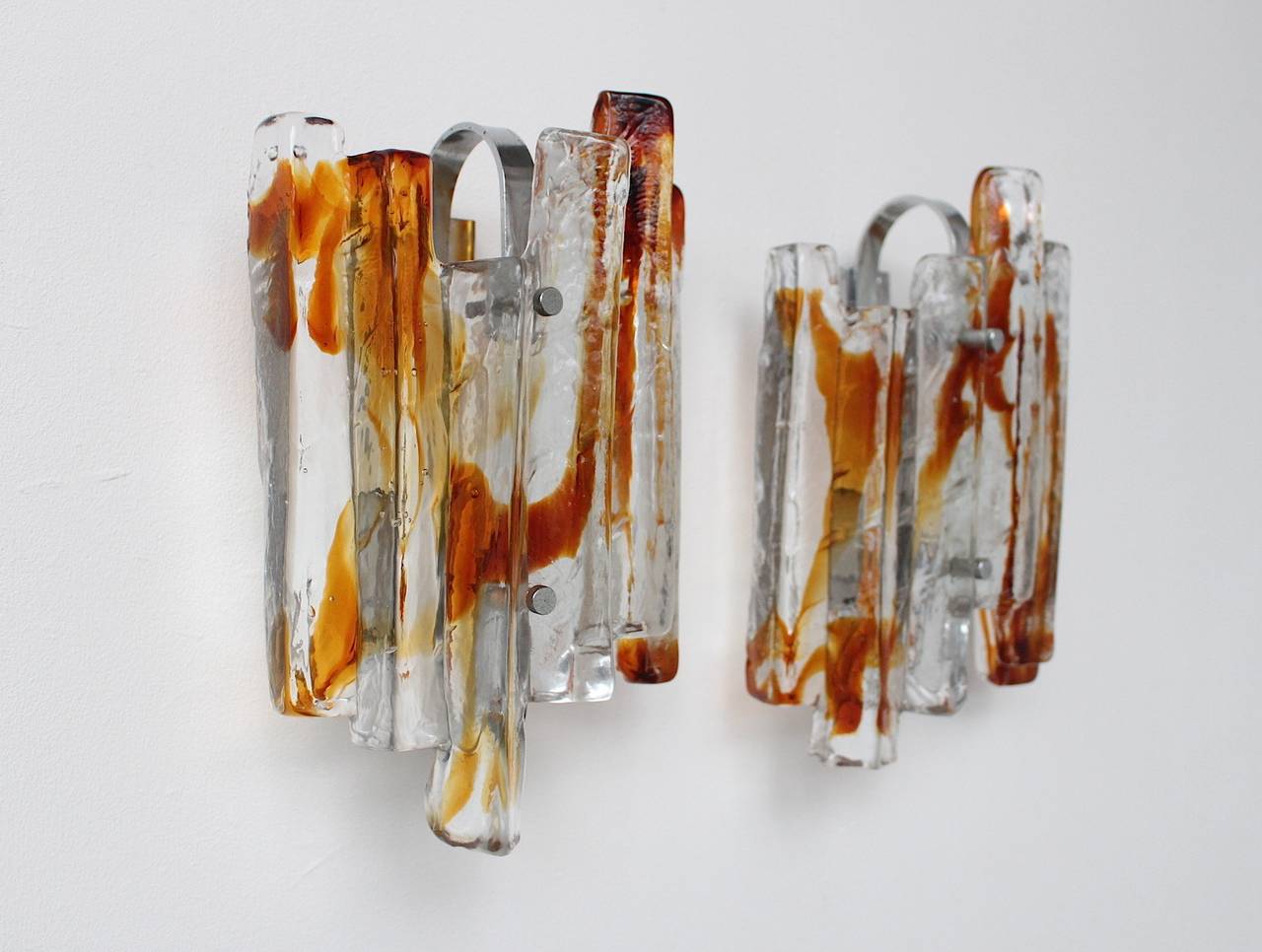 Sculptural amber and clear glass colored wall lights by Mazzega; Murano art glass pieces mounted on a chromed base. Five sconces available, also sold individually.