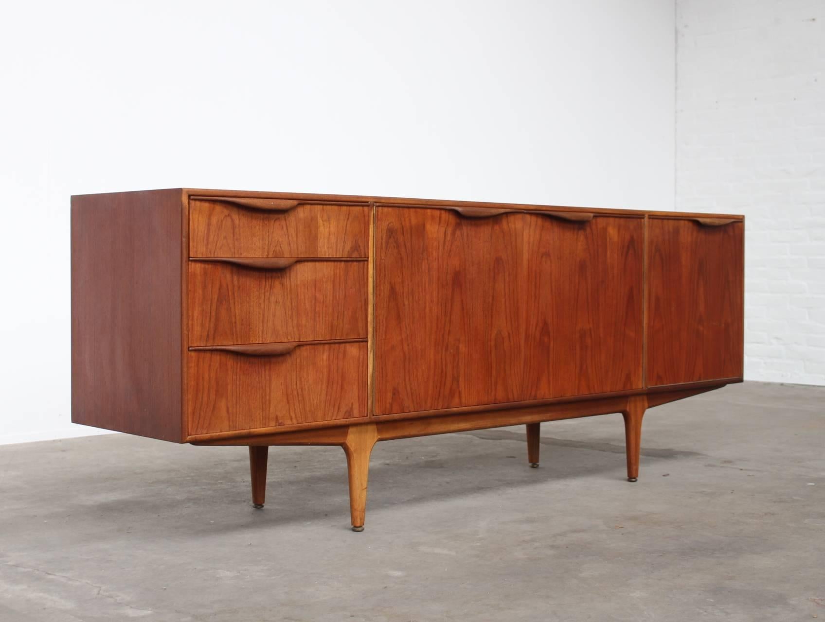 A beautiful 'Dunvegan' sideboard by cabinetmaker A.H. McIntosh & Co from Kirkaldy, Scotland.
This sideboard comes in a very warm teak an the nicely shaped handles gives it an organic caracter.
Behind the two center doors a fixed asymmetrical bar