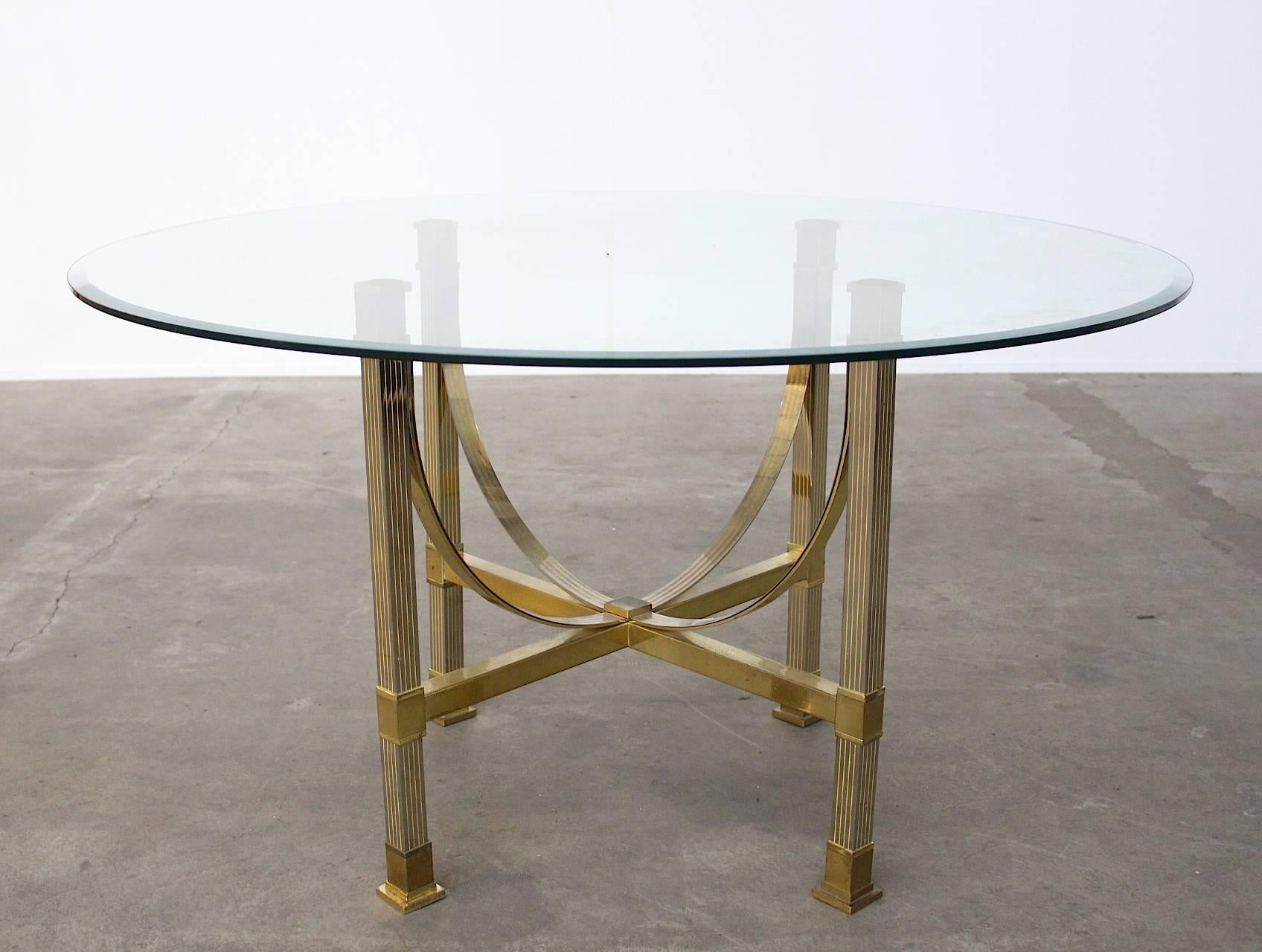 Very chic and beautiful Maison Jansen brass and glass dining table with a four leg art worked brass base and a round facet cut-glass top that easily sits six to seven people.