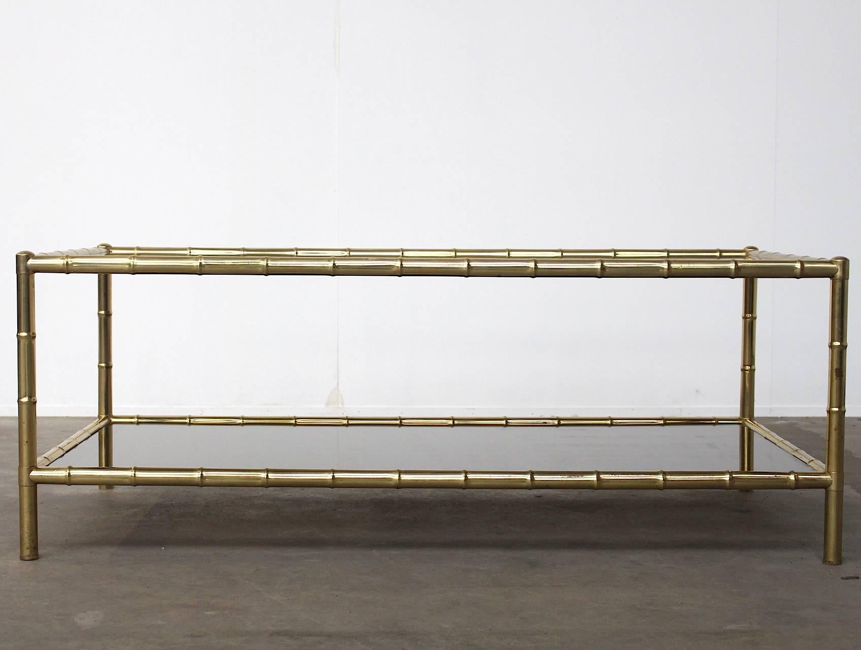 Beautiful brass-plated faux bamboo large two-tiered coffee table attributed to Jacques Adnet. It has its original glass tops with the stained outline around the edges.