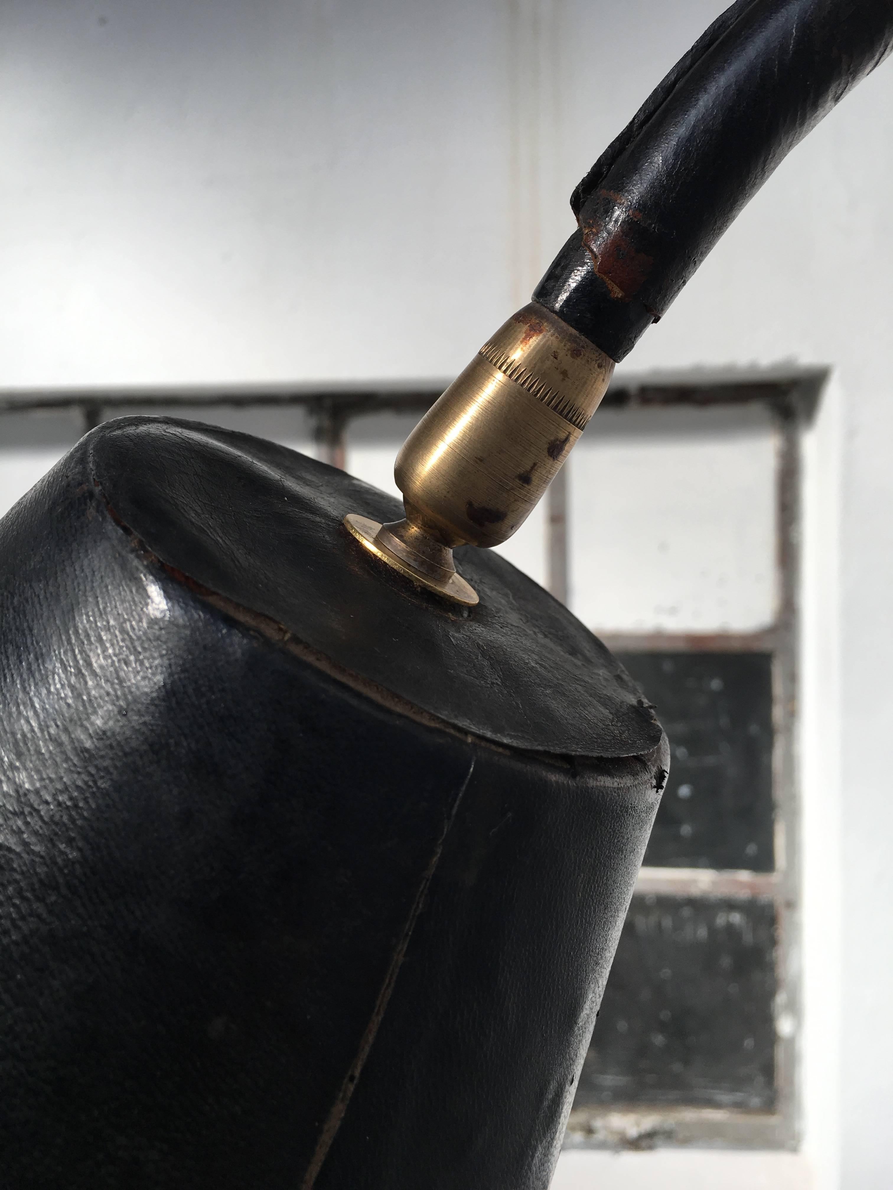 Beautiful and original Jacques Adnet floor lamp finished in original black hand-stitched saddle leather complete with all original brass details. The internal surface of the conical form reflector even still bears the original manufacturer's