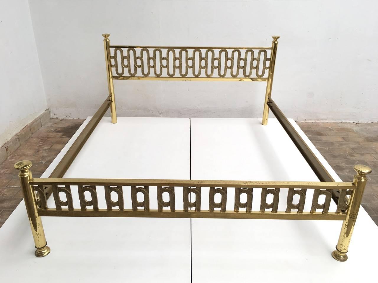 Beautifully crafted brass double bed by Italian artist Luciano Frigerio. The headboard and foot rail feature a wonderful heavy brass sculptural form interlocking loop motif with incised detailing in excellent condition The two side rails are