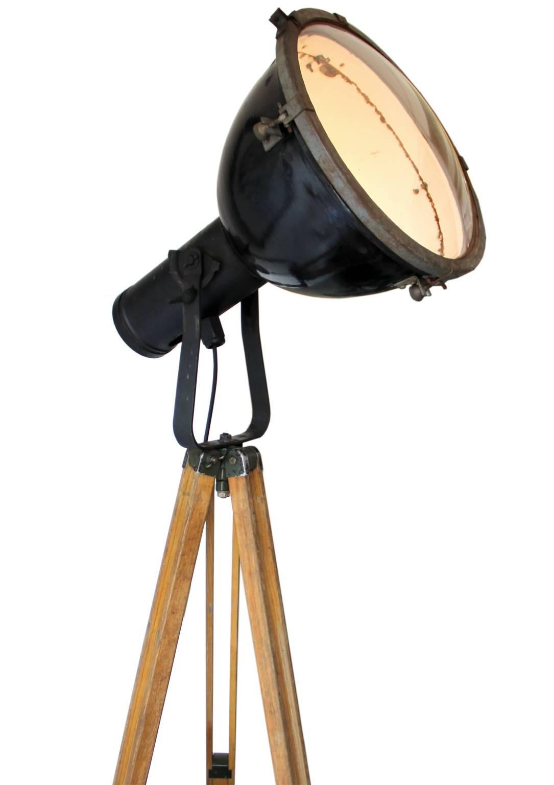 Vintage Industrial spotlight on wooden tripod. 
Adjustable height and angle. Black enamel spot white interior with original rounded glass. Diam. 38,5 cm. Max tripod height 140 cm. 
13 kg total height as on left picture: 195 cm. 

Weight: 13.0 kg /