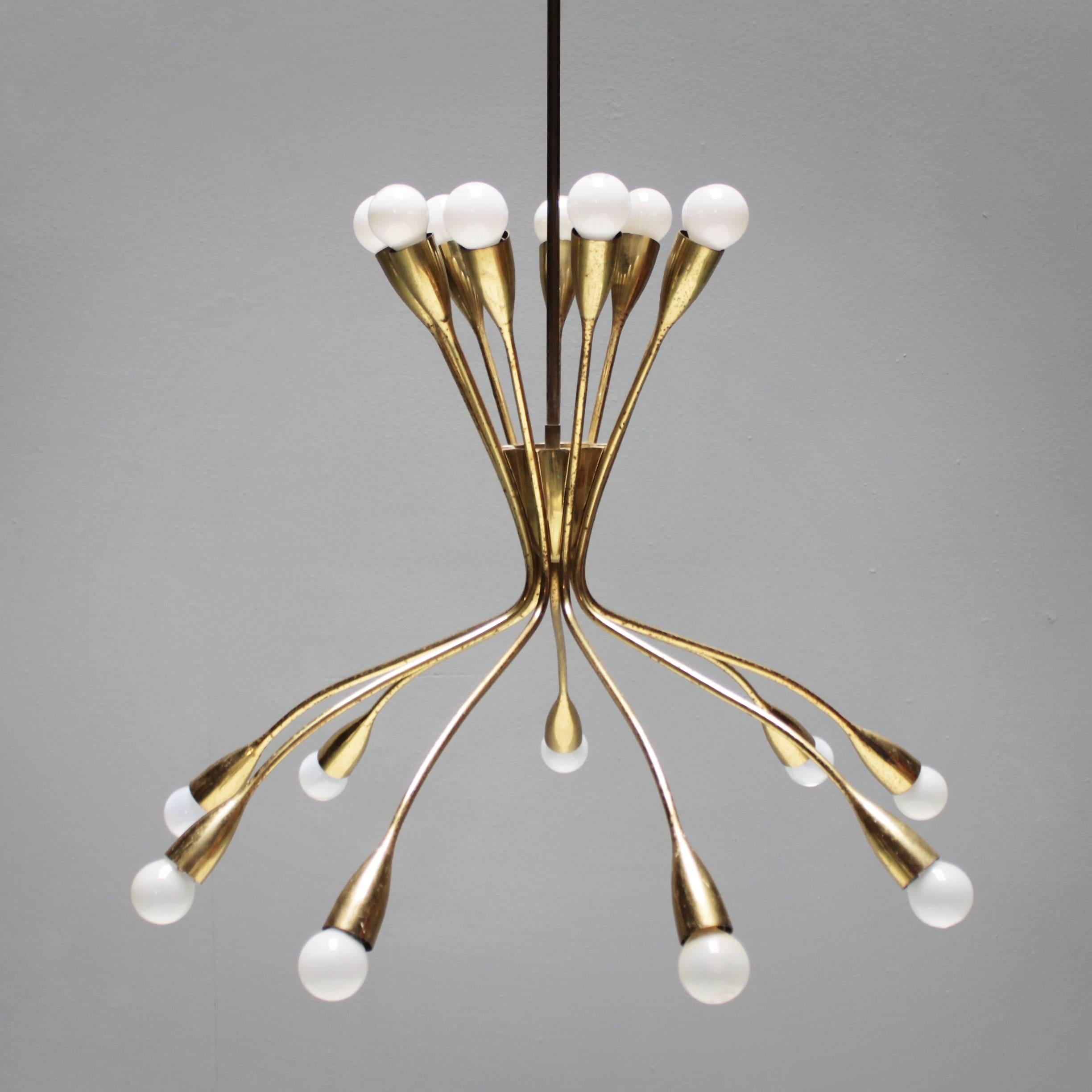 Highly decorative large brass eighteen-light fixture in the style of Stilnovo or Guglielmo Ulrich. Most likely of Italian origin. Measurements: from ceiling till drop 51.6 in. (131 cm), diameter 25.2 inches (64 cm).
