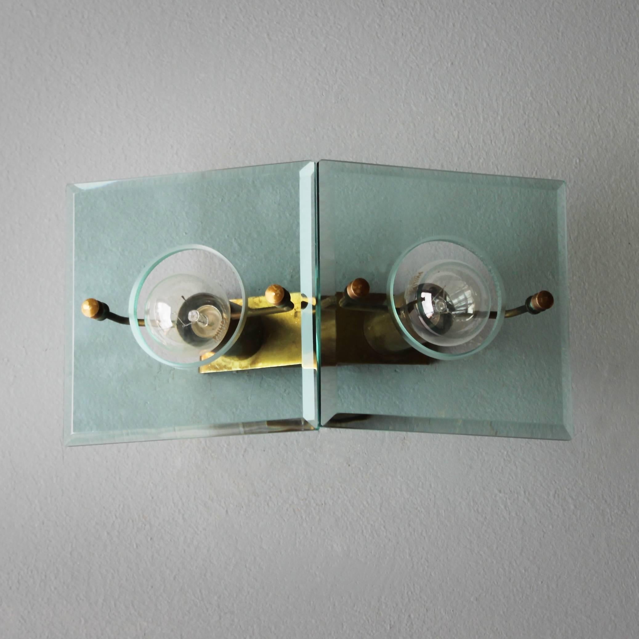 A brass and cut-glass wall light Gino Paroldo for Dino Dei, Italy. 
Dimensions: Depth 4.5 in. (11.5 cm), width 10.4 in. (26,5 cm), height 5.5 inches (14 cm).
The electricity is used but in a good condition, approved to European standards. Works in