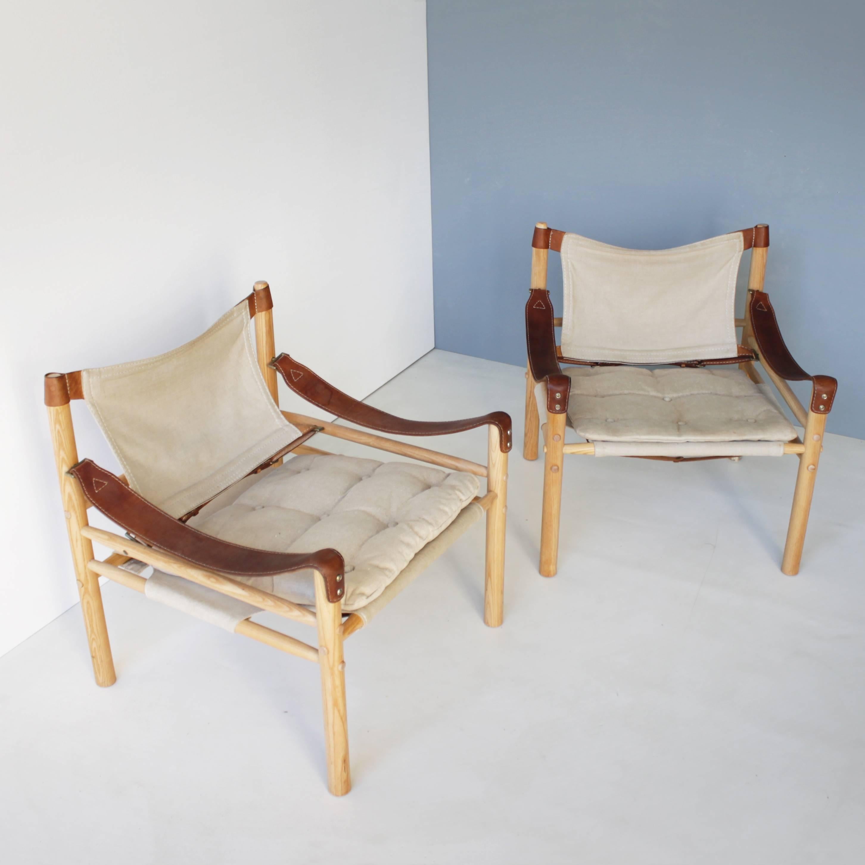 A pair of 'Scirocco' safari chairs by Arne Norell with ash frame mounted with off-white canvas, loose seat cushions with buttoned canvas covers. 
Canvas chairs are very rare. Produced by Aneby Møbler. Beautiful vintage condition. Some minor stains