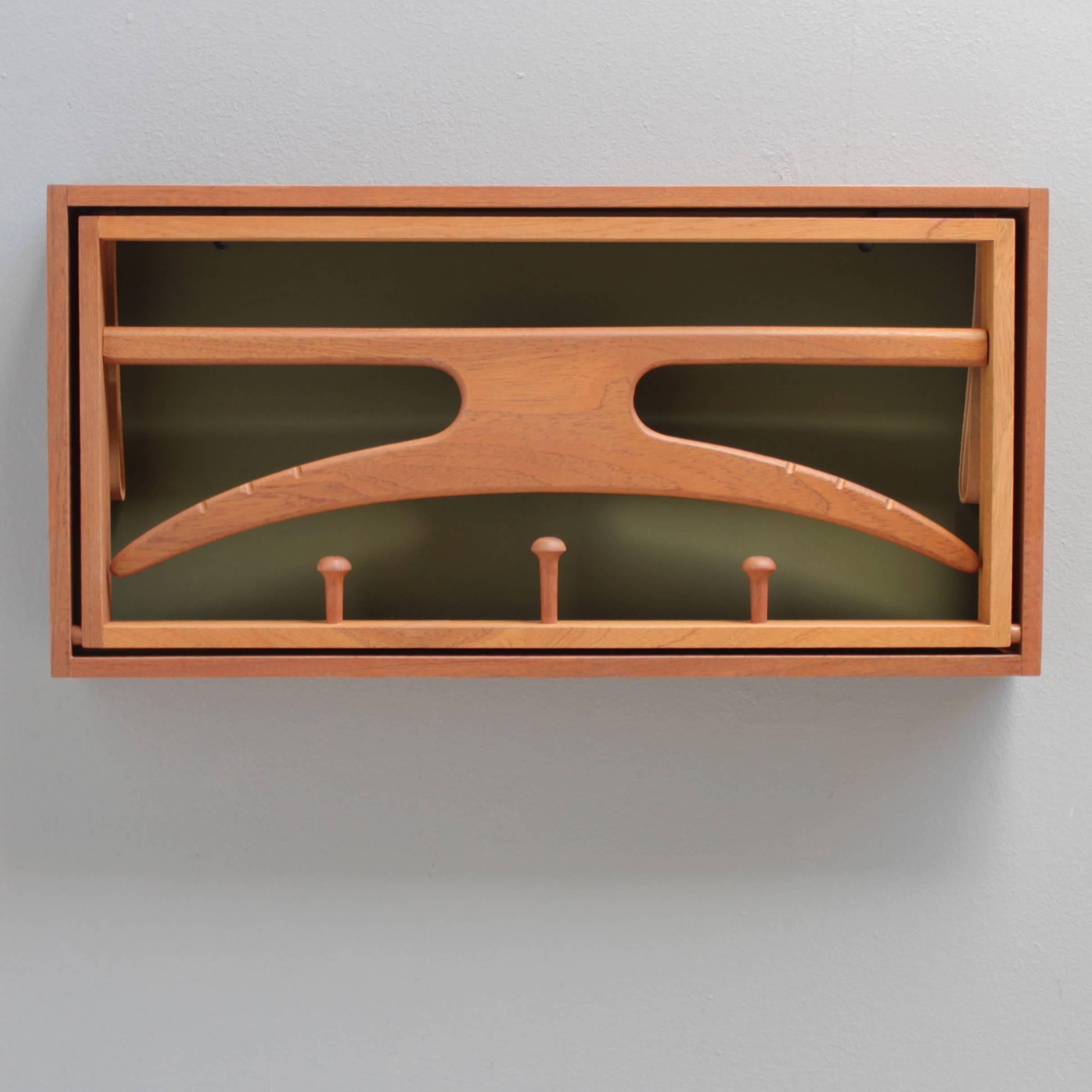 Valet by Adam Hoff and Poul Østergaard for Virum Möbelsnedkeri, Rasmussen & Brygger. Materials: Teak wood, natural leather straps and green formica back. In excellent condition, seemingly never used. Dimensions: depth 2.55 in. (6,5 cm), width