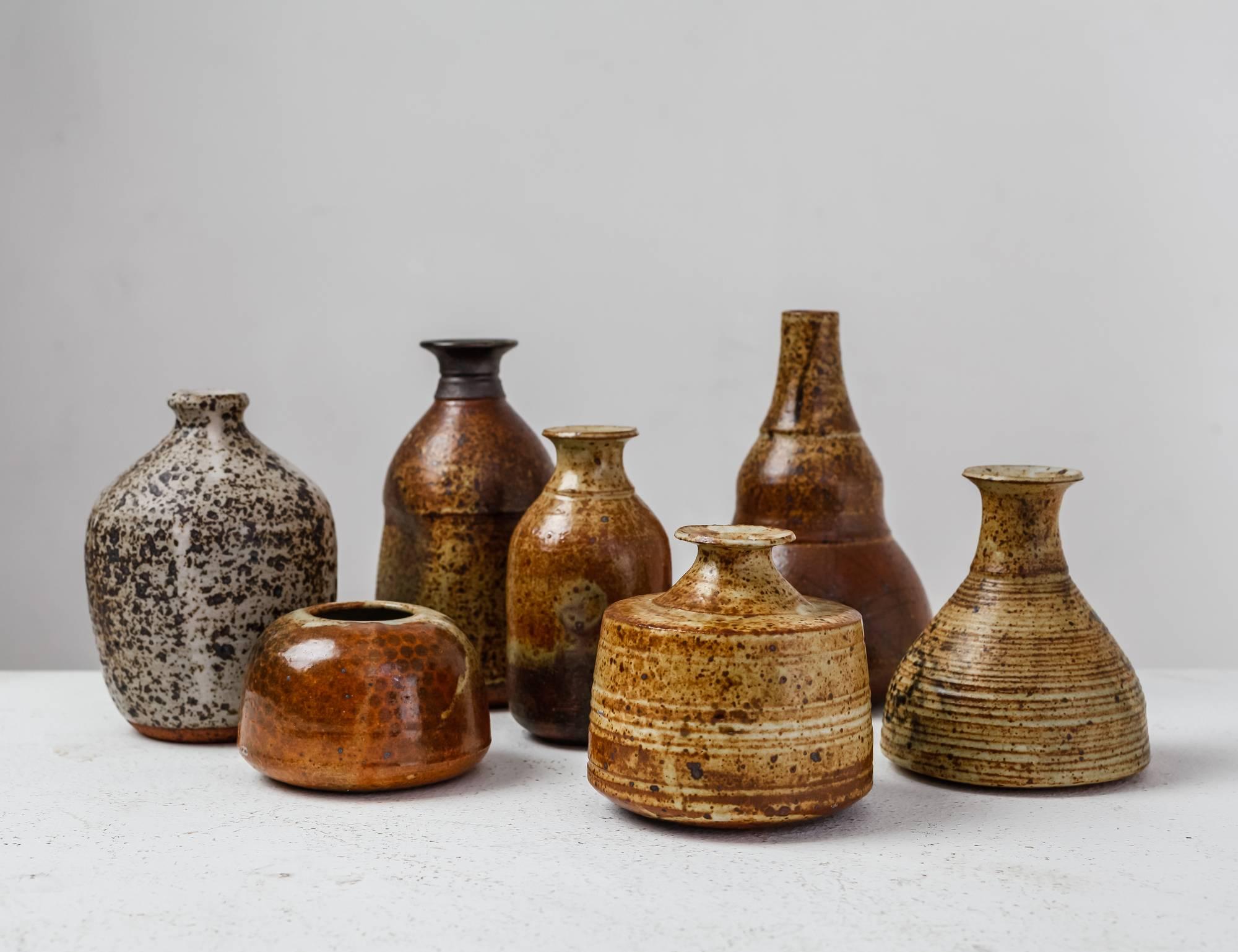 A set of seven vases with a brown and earth tone glaze finish, by French ceramist Franco Agnese. 
Measures: The lowest piece is 6.5 cm (2.5 inch) high and has a 9 cm (3.5 inch) diameter. The tallest vase is 16.5 cm (6.5 inch) high with a 10.5 cm (4