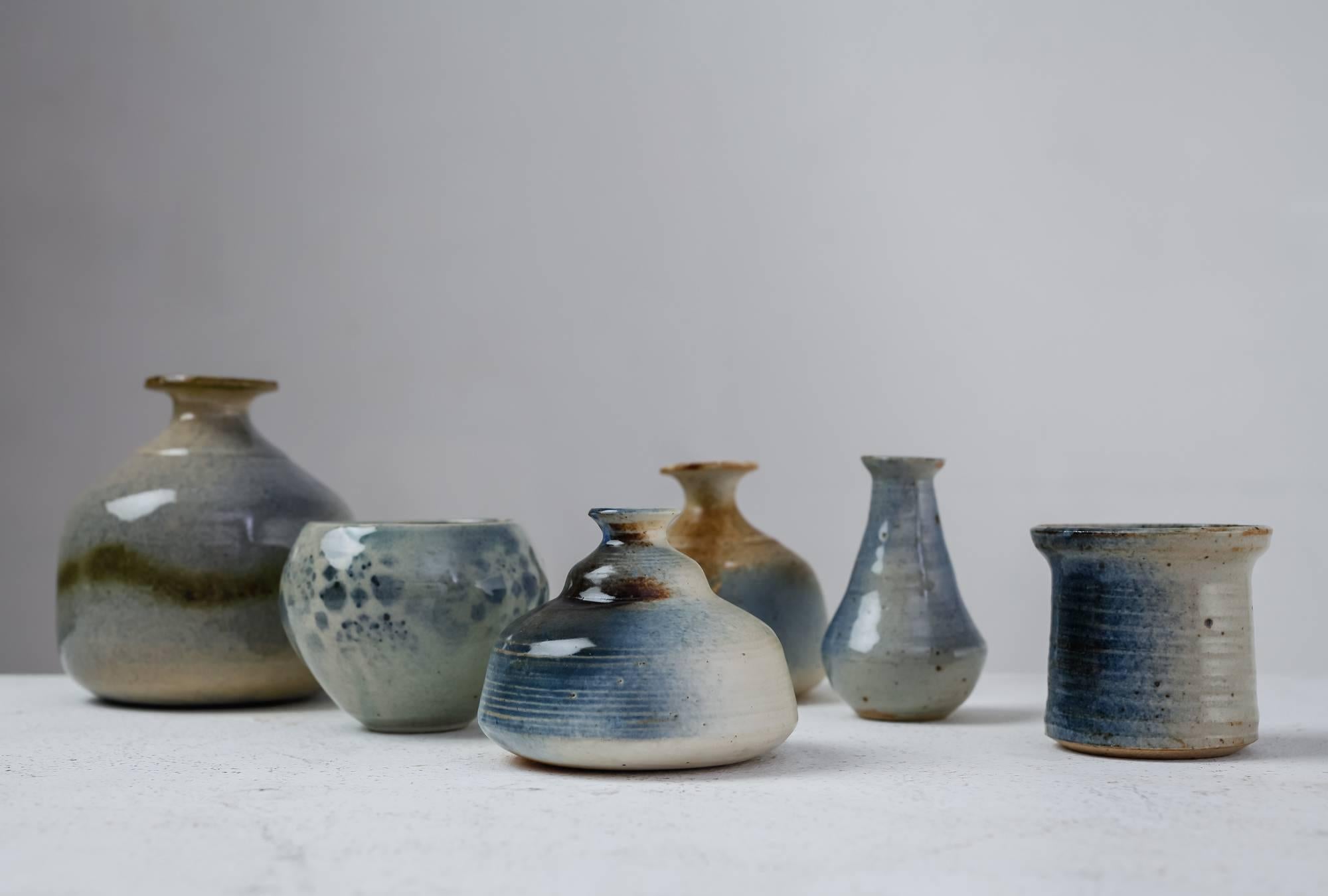A set of six vases with a mostly blue and grey glaze finish, by French ceramist Franco Agnese. 
The lowest piece is 7 cm (2.7