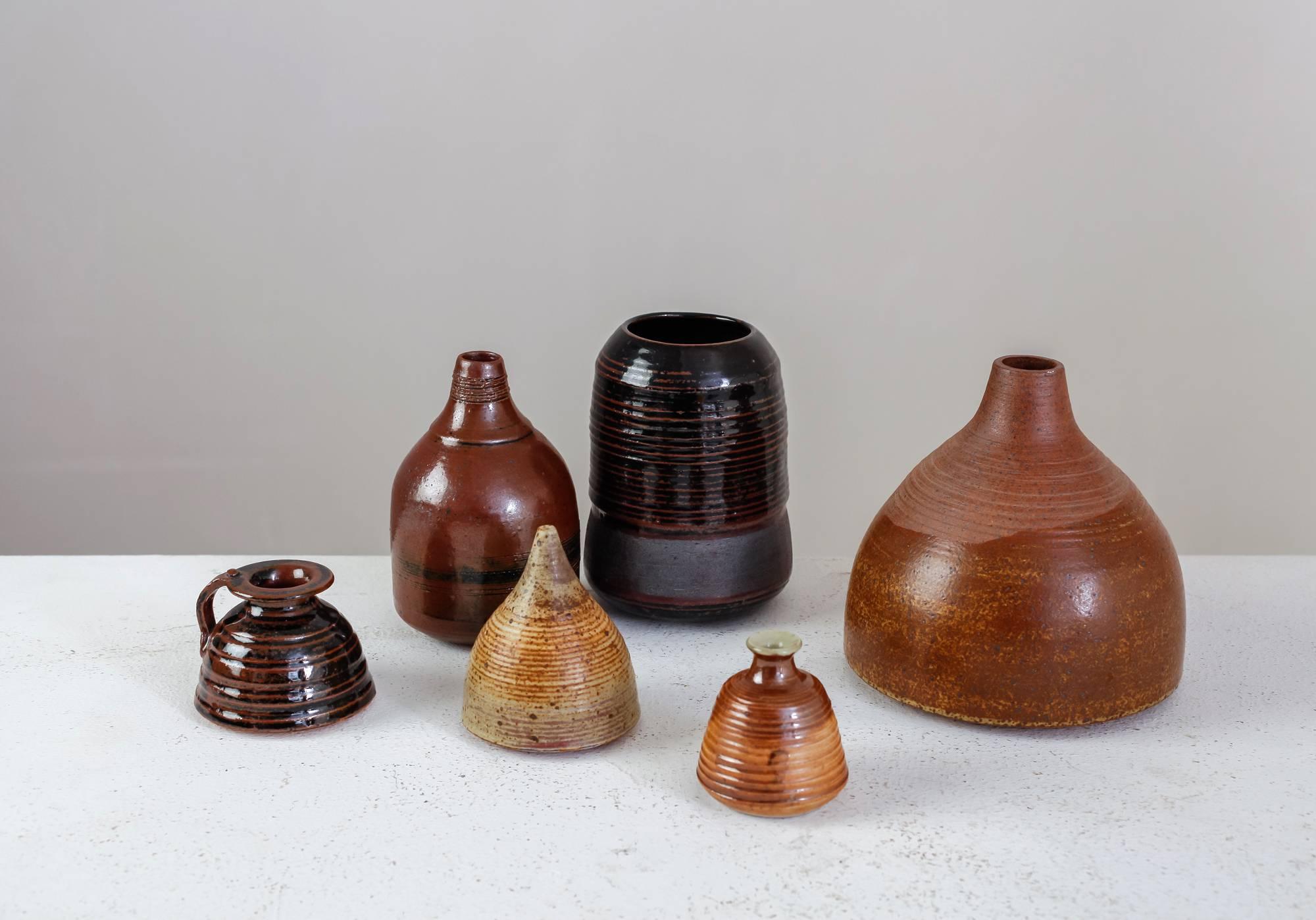 A set of six vases in a brown to nearly black glaze finish, by French ceramist Franco Agnese. 
The lowest piece is 7.5 cm (3 inch) high and has a 6 cm (2.4 inch) diameter. The tallest vase is 15.5 cm (6.1 inch) high with a 16 cm (6.3 inch)