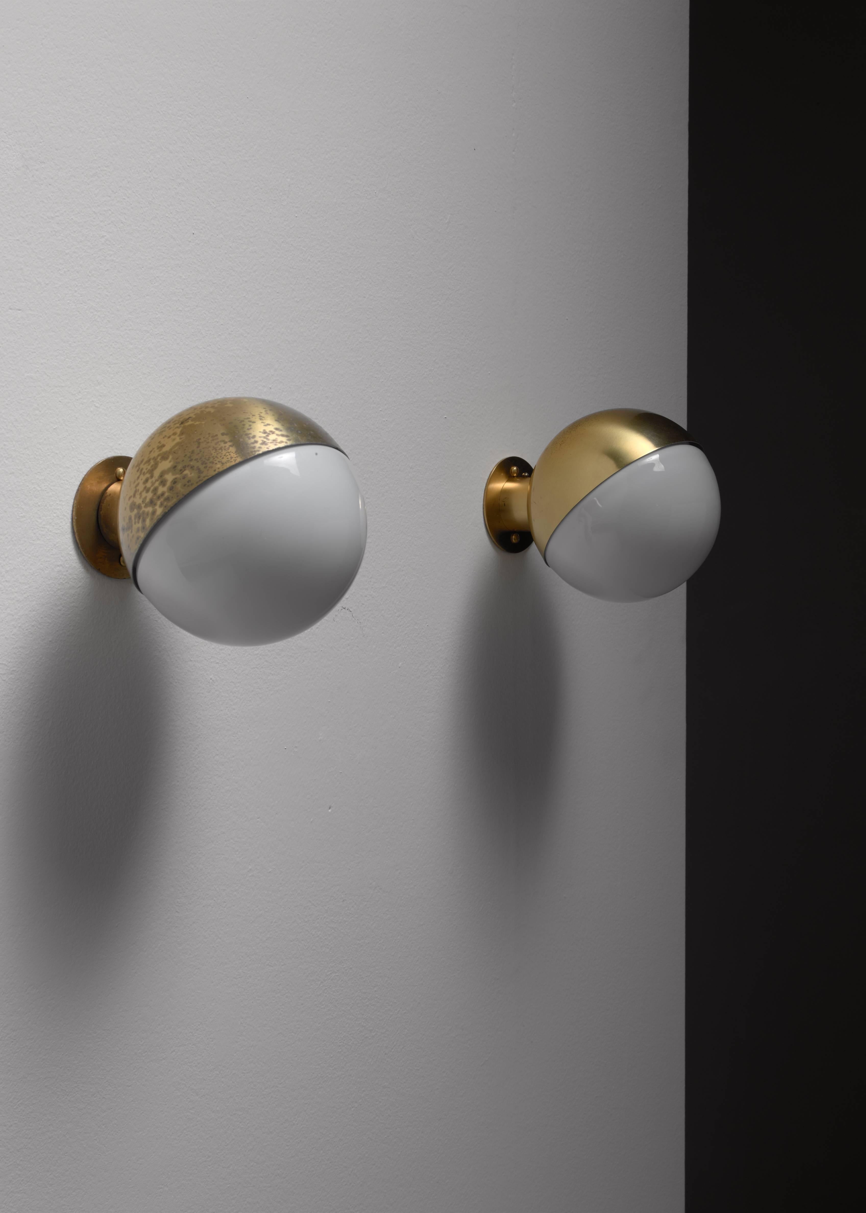 A pair of model 10630 wall lamps designed by Vilhelm Lauritzen for Louis Poulsen. The lamps are made of a beautiful middle aged brass base with a hemisphere shaped opaline glass diffuser. The lamp scan be screwed to the wall with the light facing