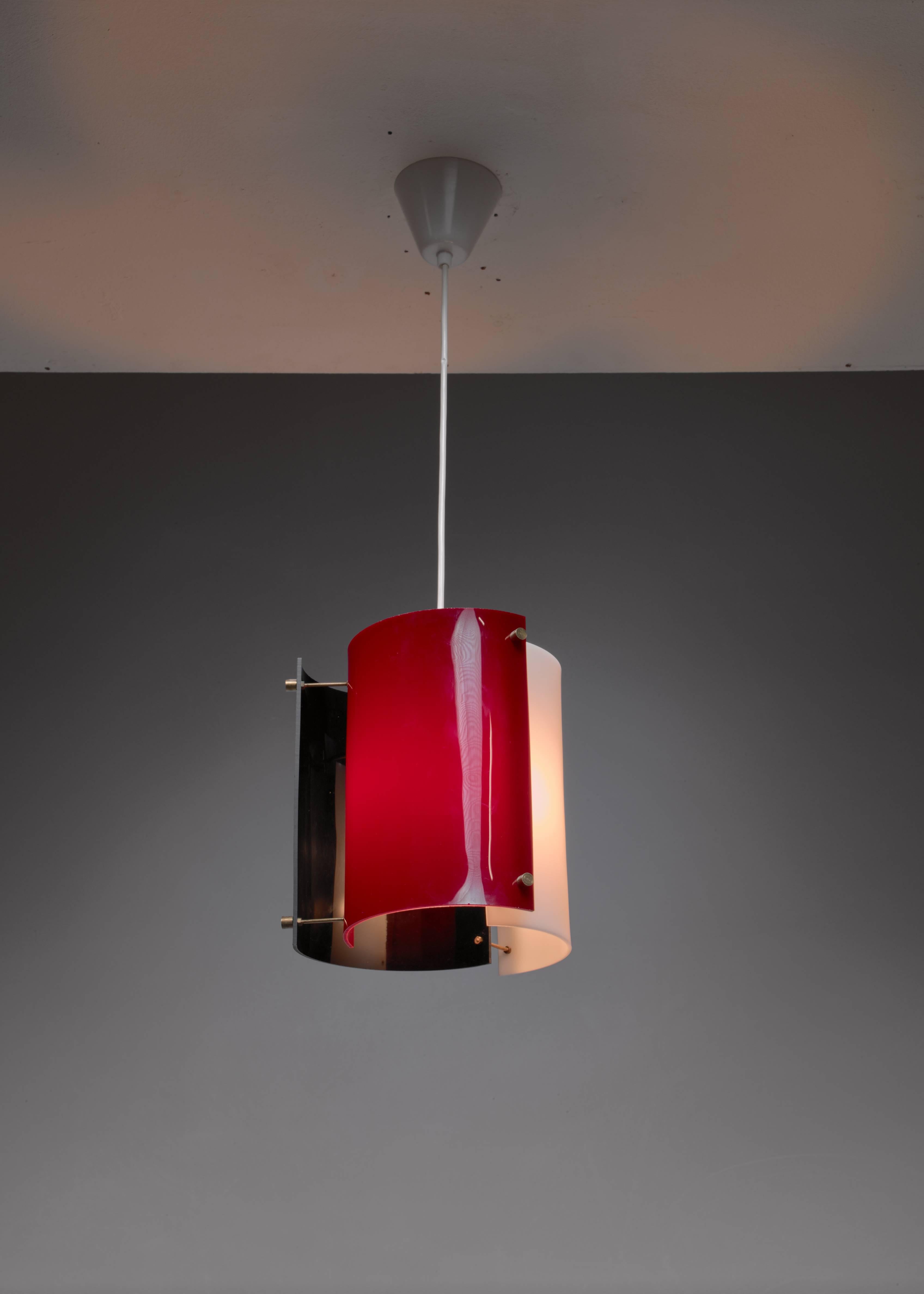 A Yki Nummi 1960s pendant for Orno. The lamp is made of three semicircular plexiglass elements in white, black and purple, held together with thin brass rods. The colored plexiglass creates a beautiful, atmospheric light. A variation with a peach,