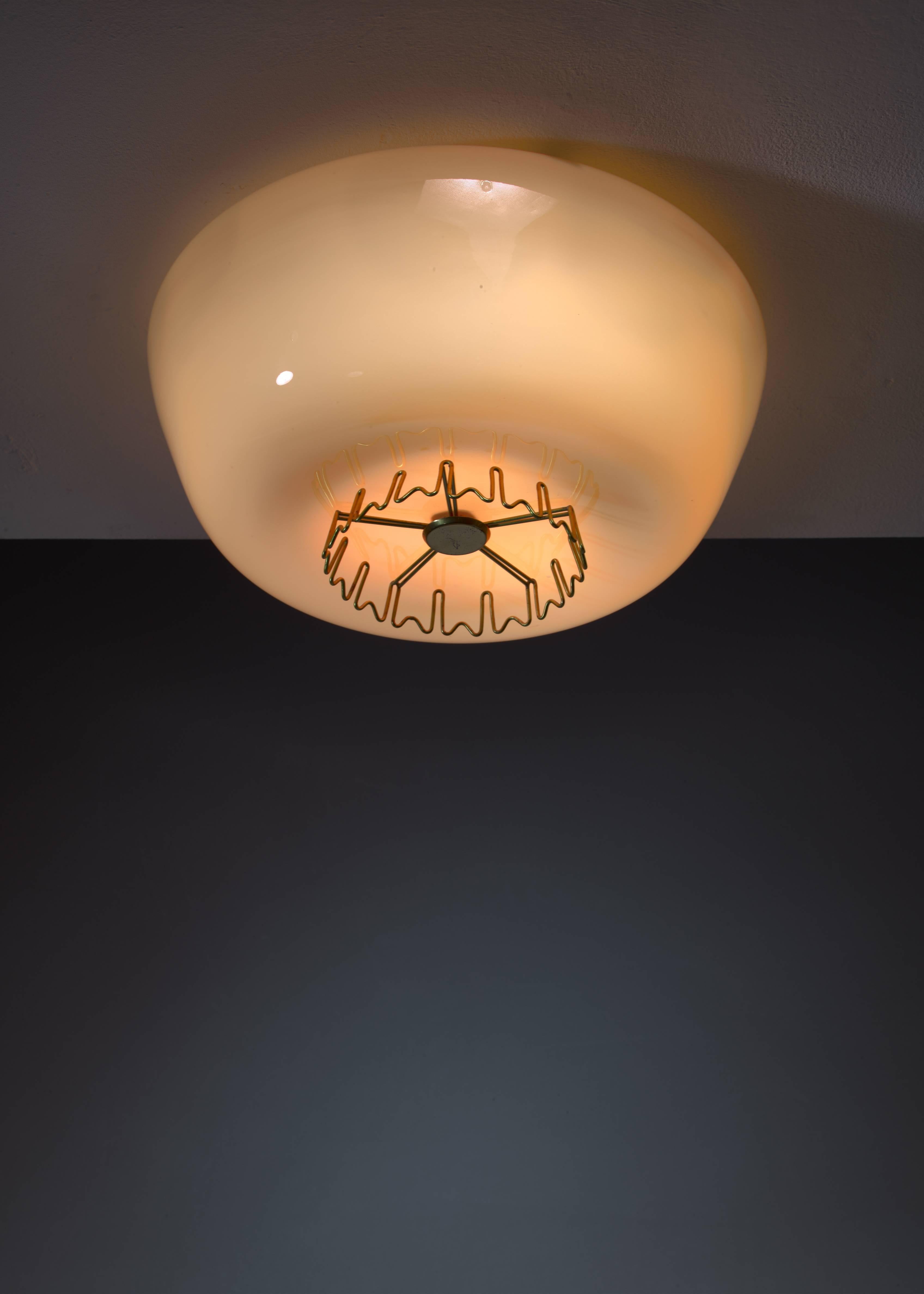 A Lisa Johansson-Pape yellow model 1116 flush mount ceiling lamp with a brass crown decoration. The shade is made of two layers of glass; white inside and yellow outside, giving it a beautiful and warm light. The lamp has three E27 light bulbs and