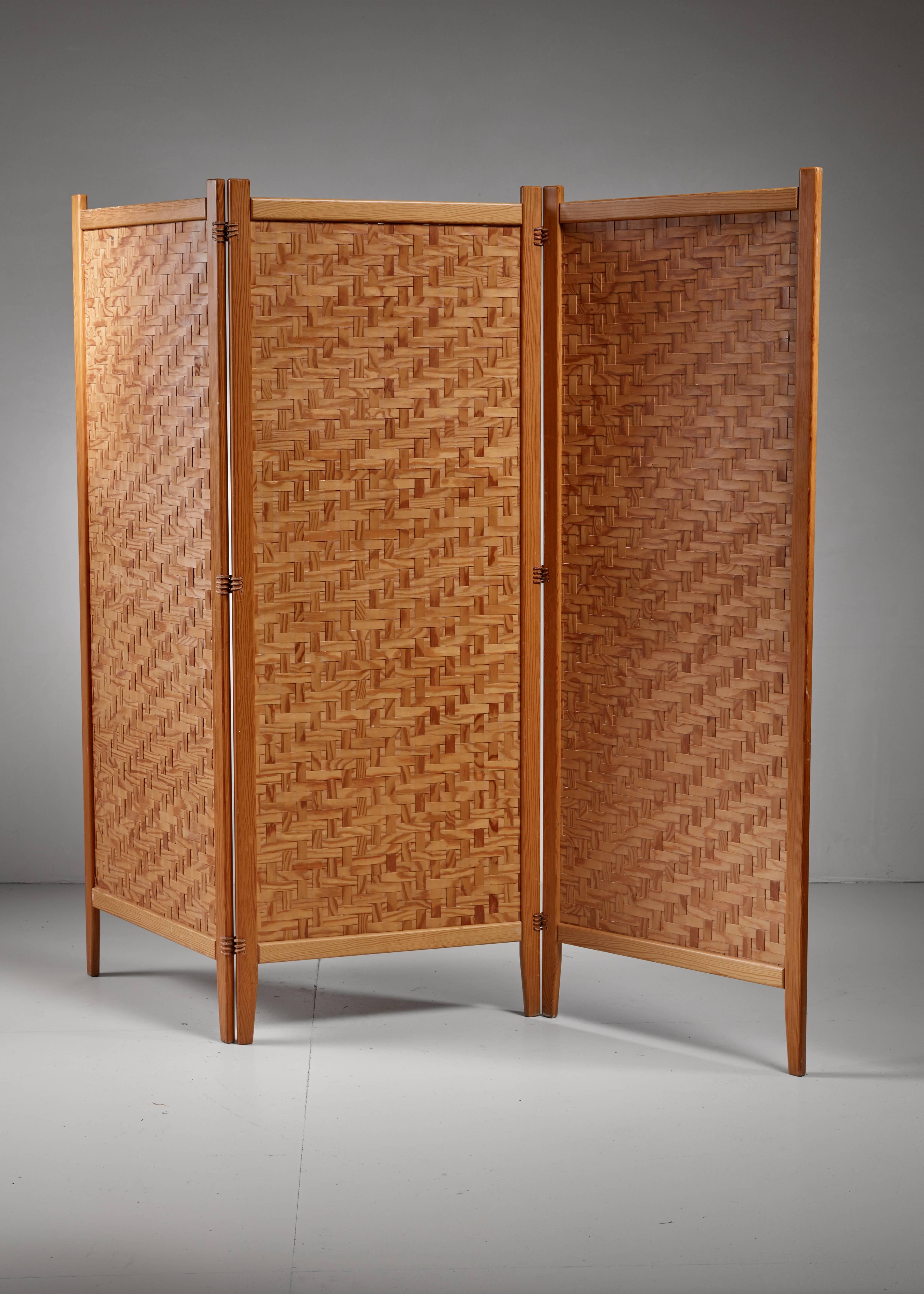 A Swedish folding screen or room divider by Alberts, Tibro. The three-part screen is made of a pine frame with thin, woven pine strips. The three panels are connected with leather strings.