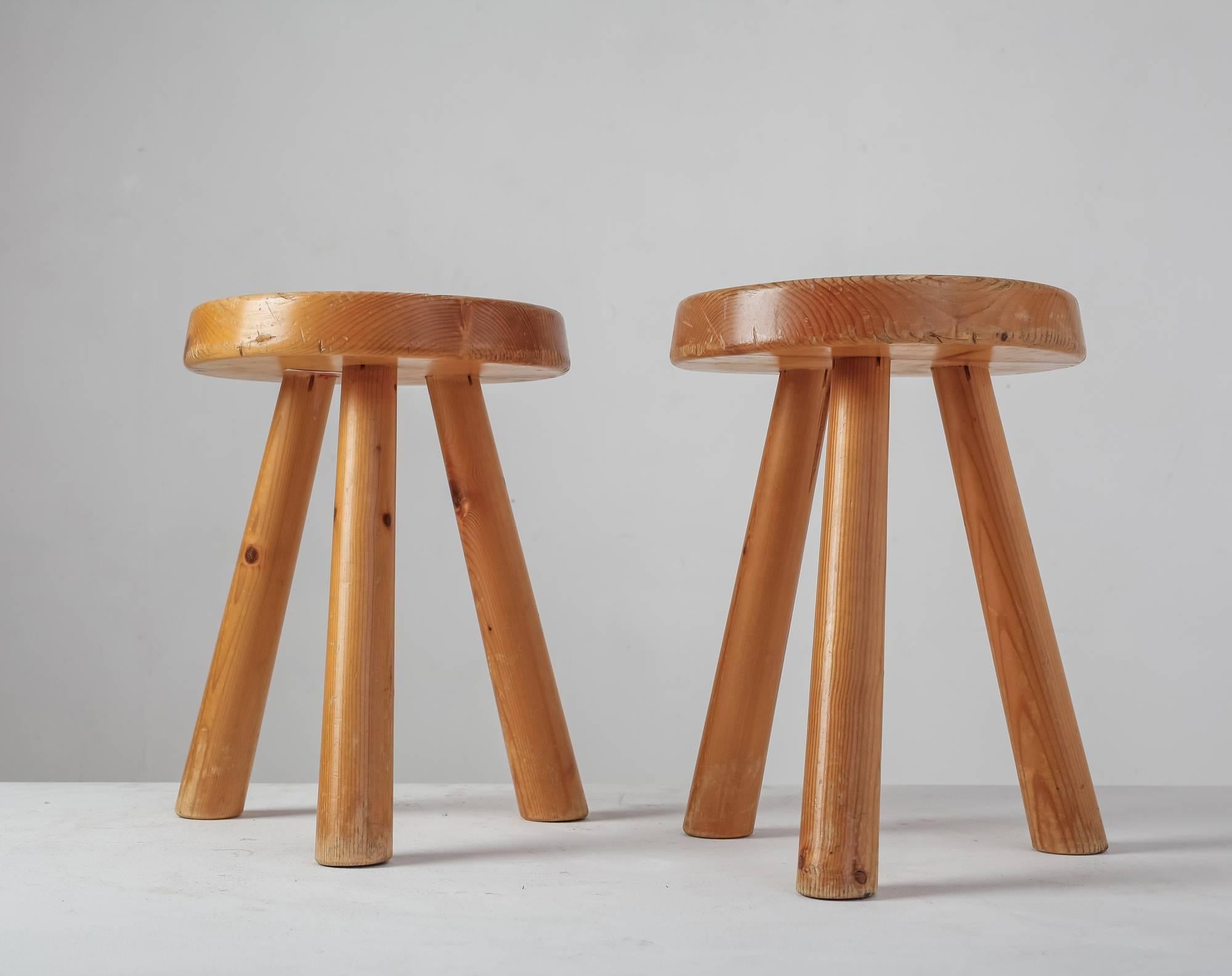 A pair of tripod pine Charlotte Perriand stools with a round seating with a diameter of 32 cm (12.5
