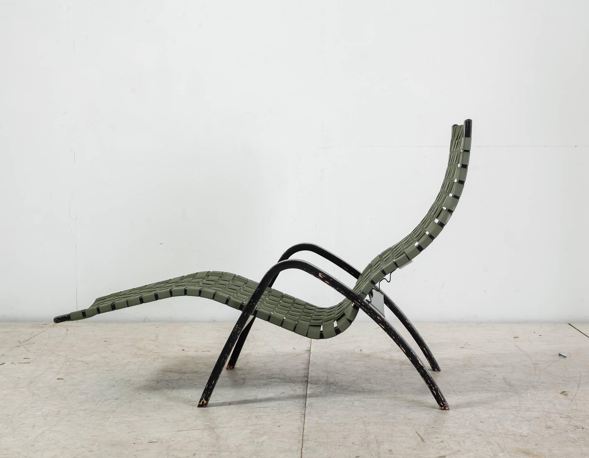 A Clifford Pascoe chaise longue, made of a black lacquered bent maple frame, with a green canvas webbing. The loose seating can easily be placed in three different positions.

There are some damages to the paint, but the chair is in an overall