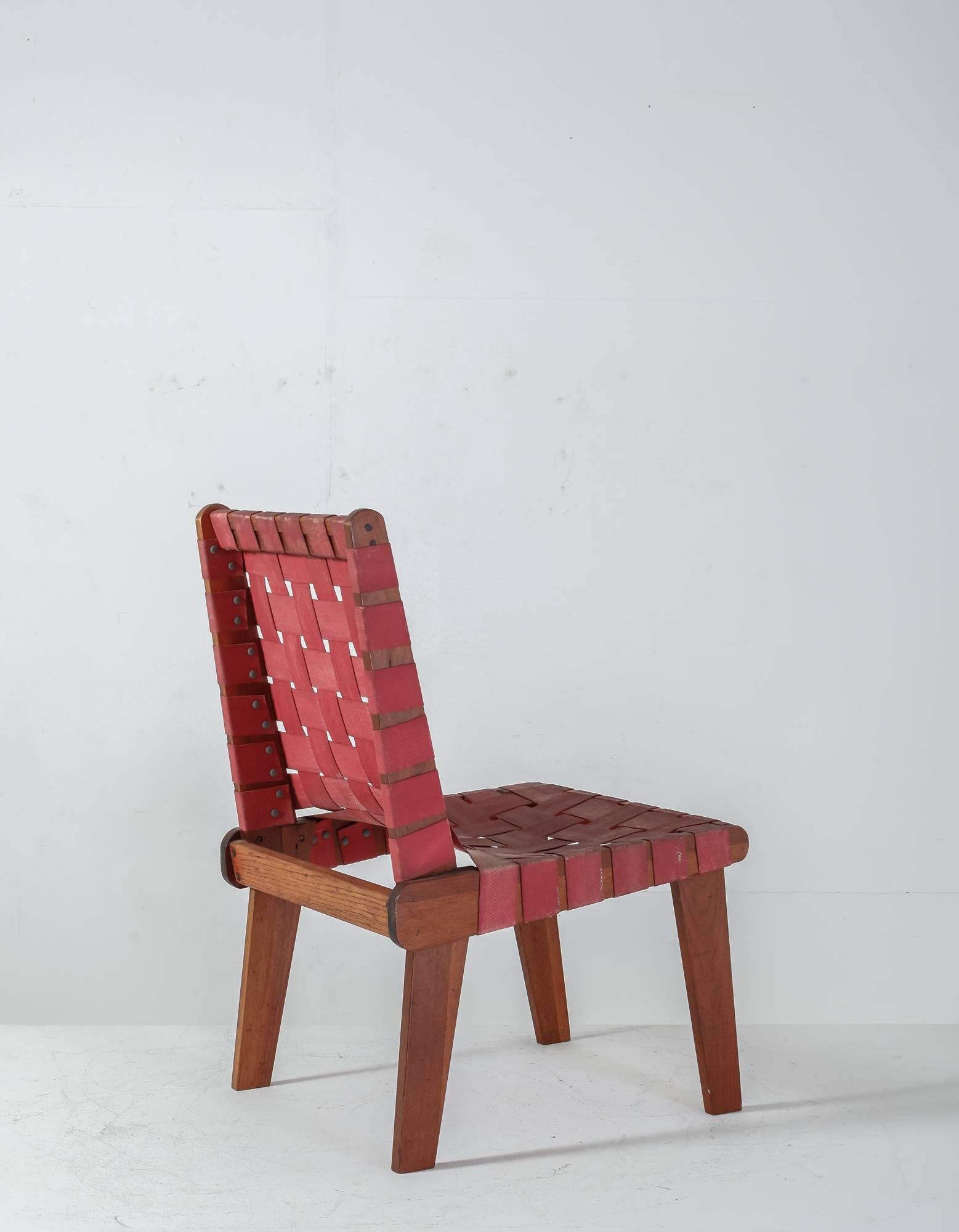 A minimal side chair with red webbed canvas seat and back reminiscent Klaus Grabe.

 
