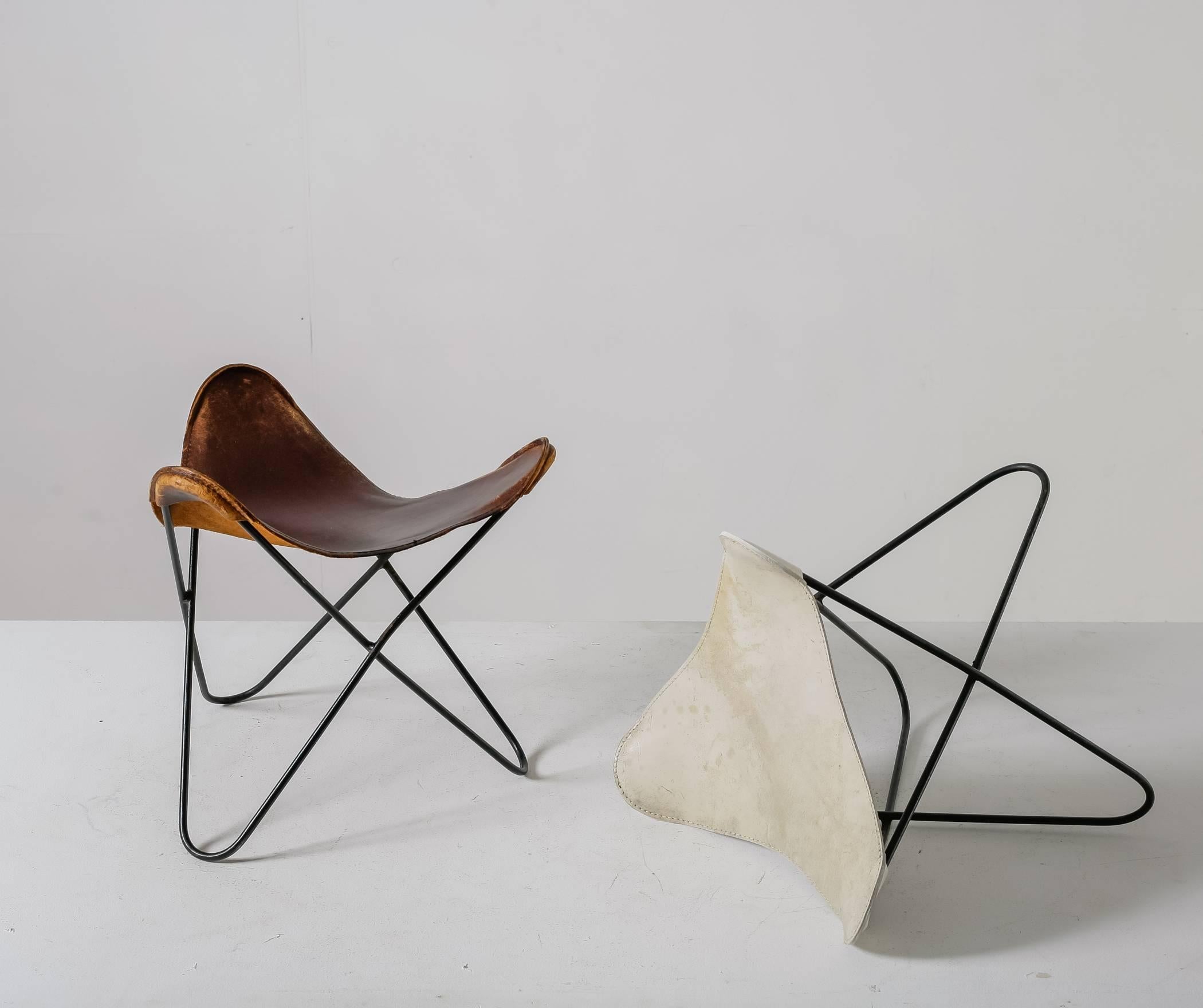 A pair of iron with leather Butterfly ottomans or stools, by Argentinian architect Jorge Ferrari-Hardoy for Knoll. One has a brown and the other has a white leather seating.
This model can be used as an ottoman in combination with a BKF butterfly