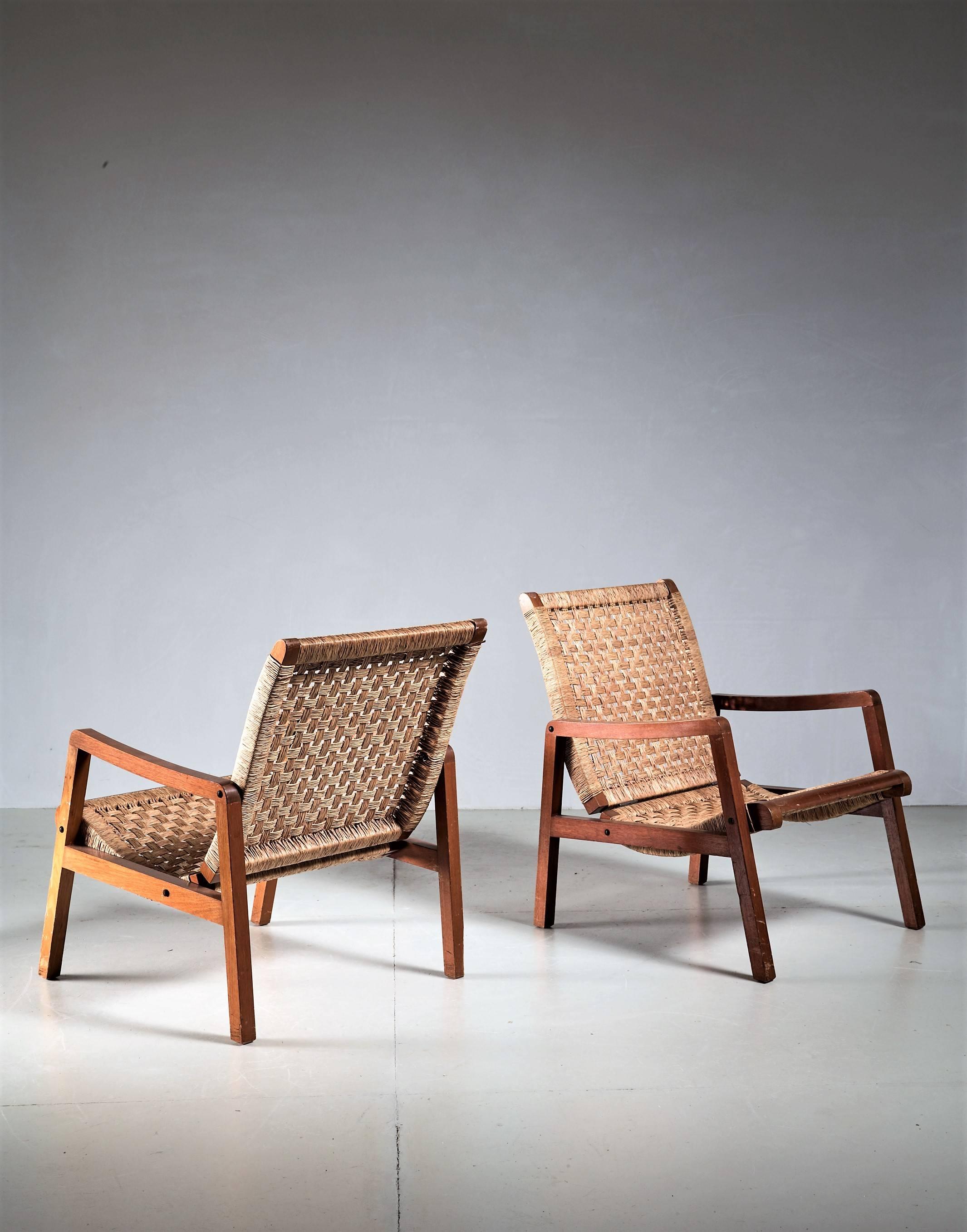 A pair of Mexican armchairs in a style reminiscent of Michael van Beuren and Domus. The chairs are made of a slender wooden frame and a curved seating with a woven cane upholstery.