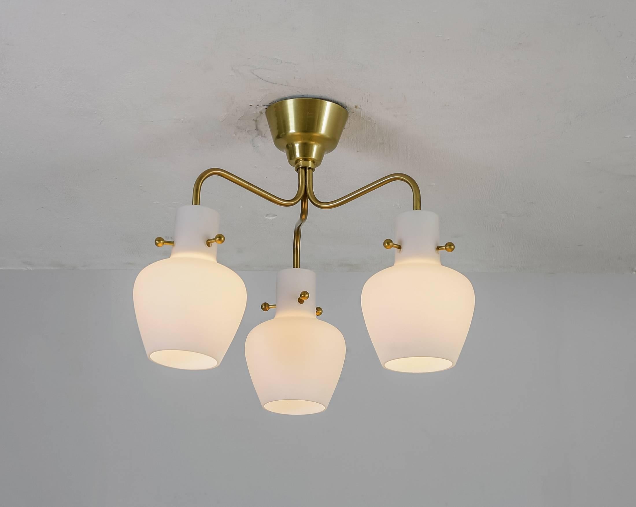 A three shaded flushmount chandelier by Hans Bergström for Ateljé Lyktan, Sweden, 1940s
The lamp is made of three brass arms with opaline bell-shaped glass shades, fixed with decorative brass screws.

Published and in a good condition.